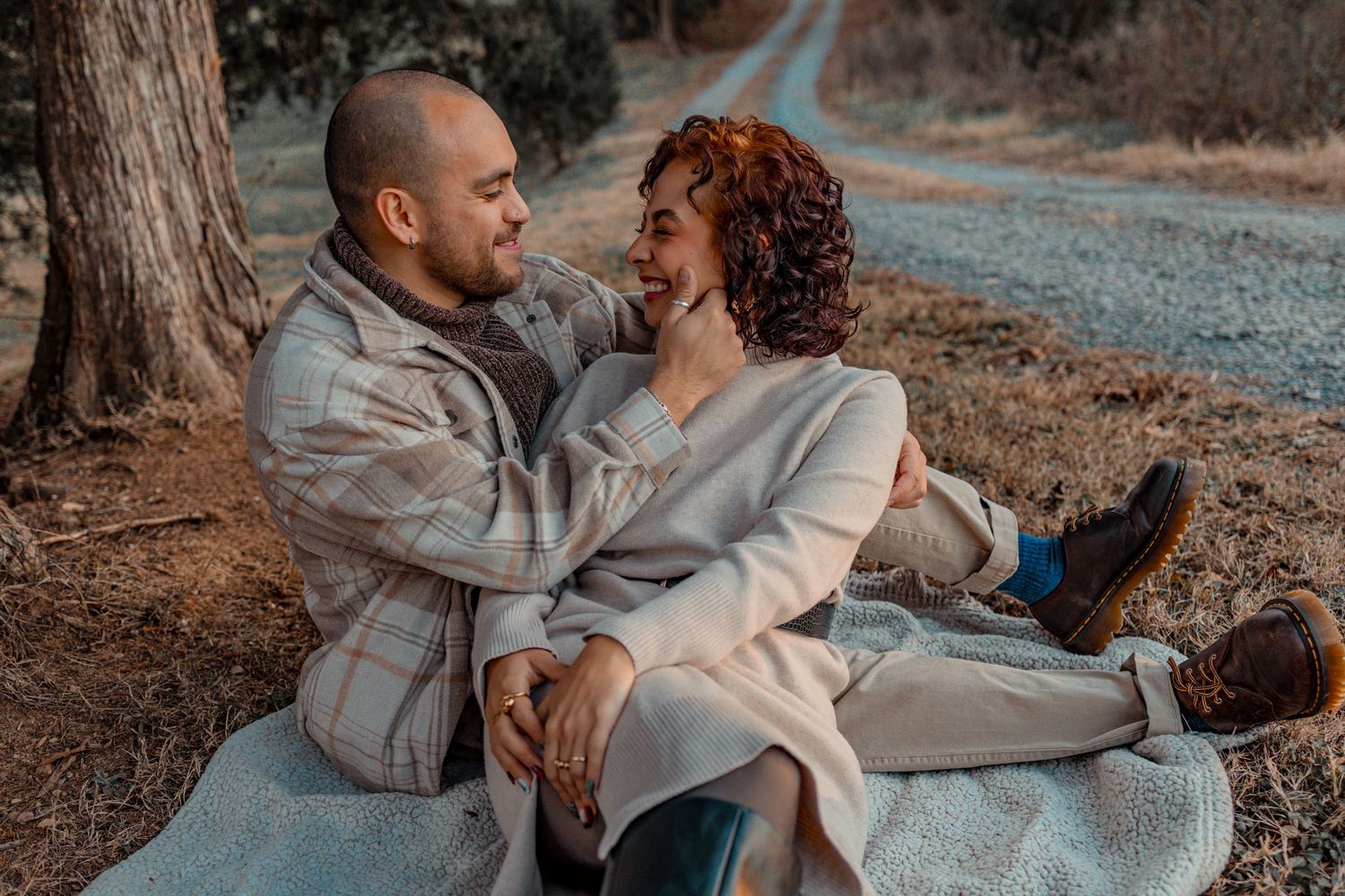 Couple sharing intimate moments together outdoors in casual attire during a photo session.