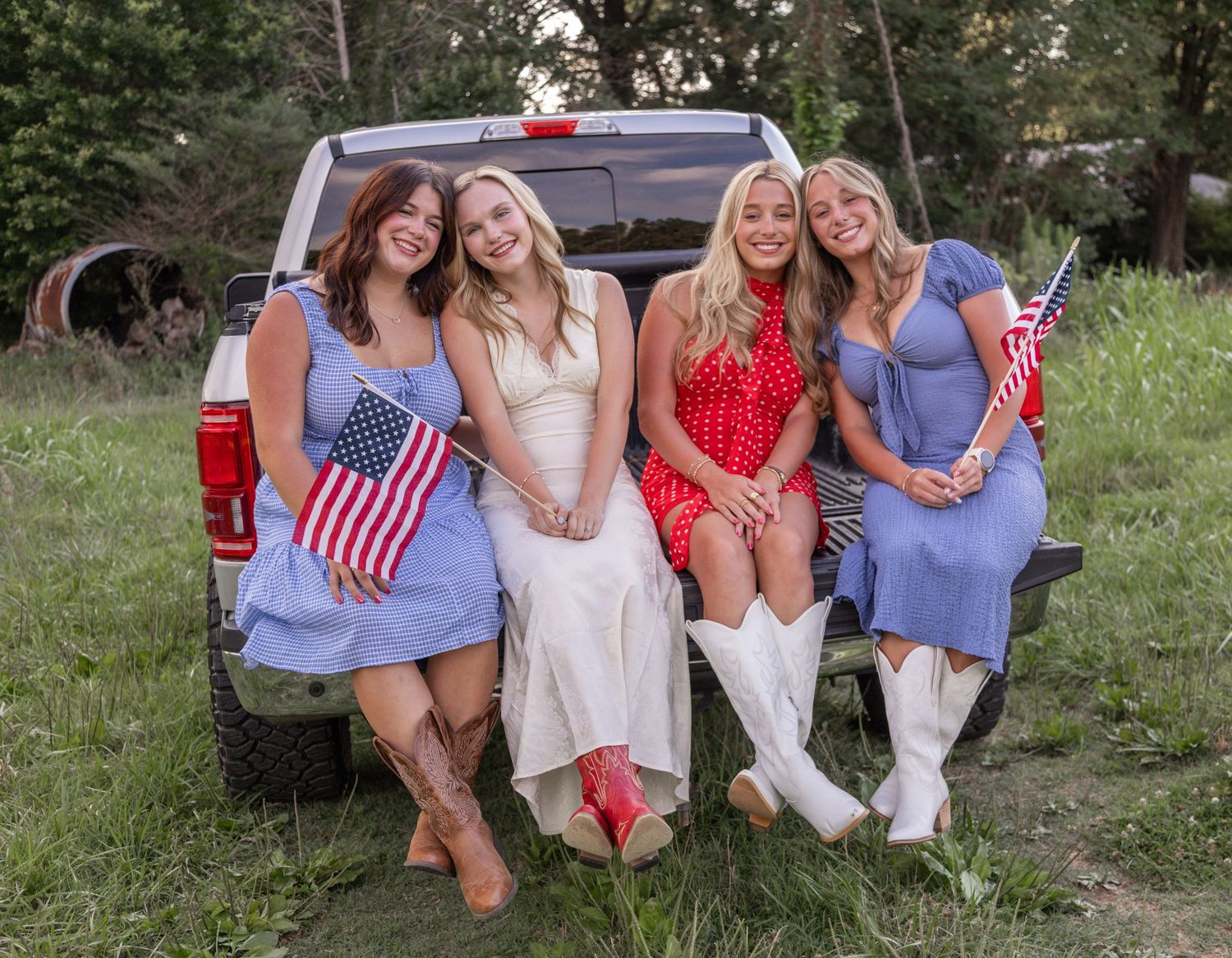 A group poses together wearing red white and blue patriotic outfits in a casual outdoor summer setting.