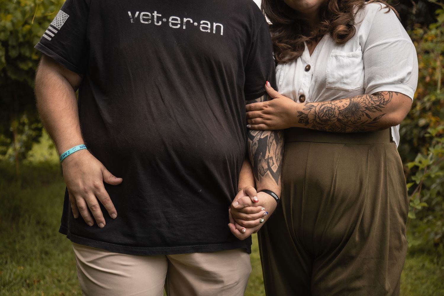 A close-up of two people holding hands in a garden setting.