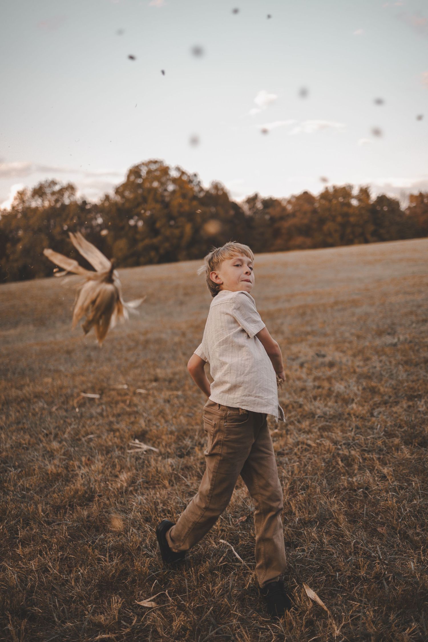 A child plays joyfully in a golden field at sunset, running and spinning with carefree abandon.