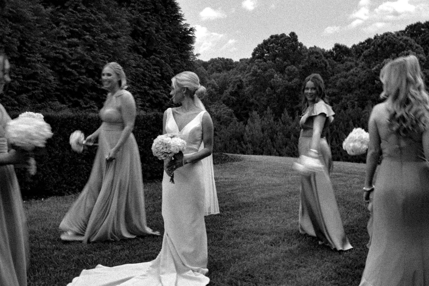 Black and white photo of wedding party lineup in outdoor garden setting.