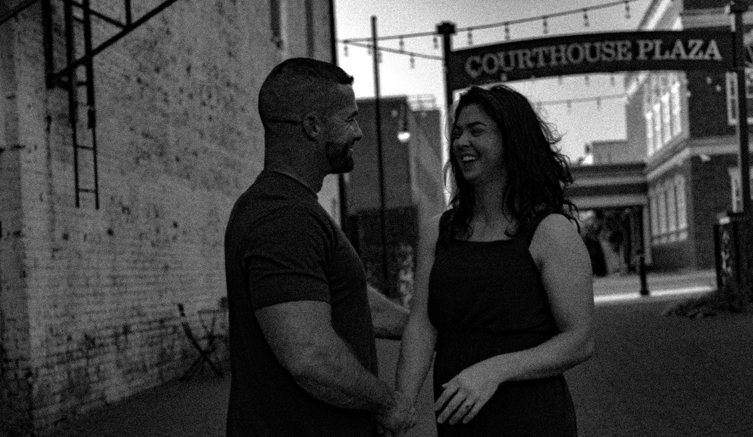 A candid black and white moment shared between a couple near a vintage building.