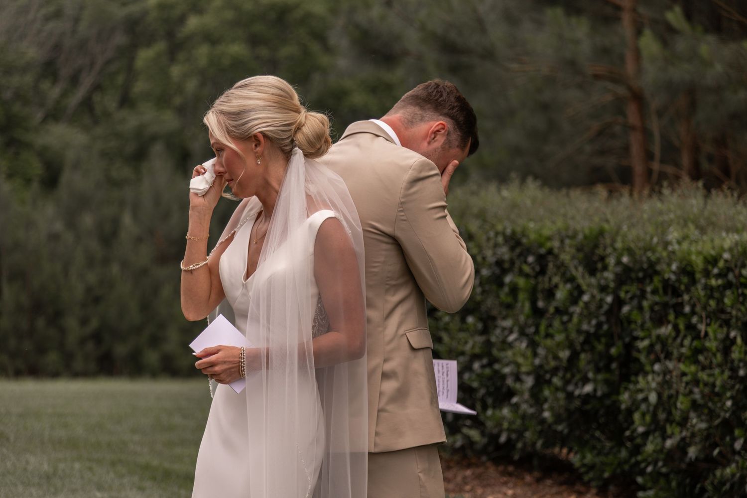 Newlywed couple sharing an intimate dance moment outdoors with bridesmaids in soft blue dresses looking on.