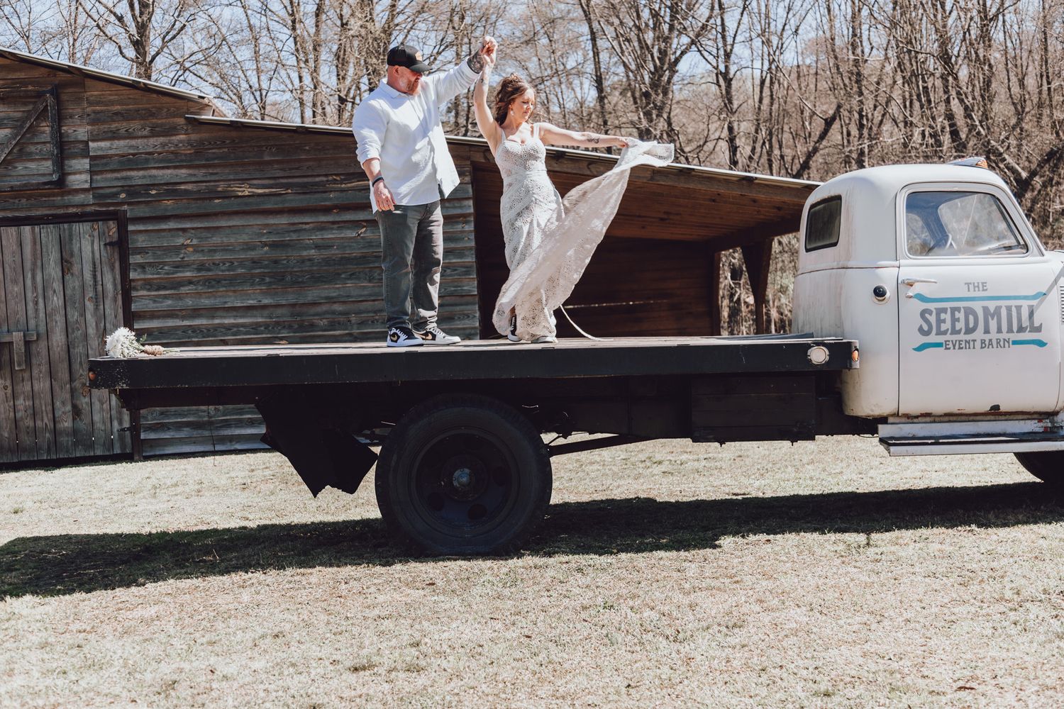 A couple standing on a flatbed truck from The Seed Mill during a rustic outdoor photoshoot.