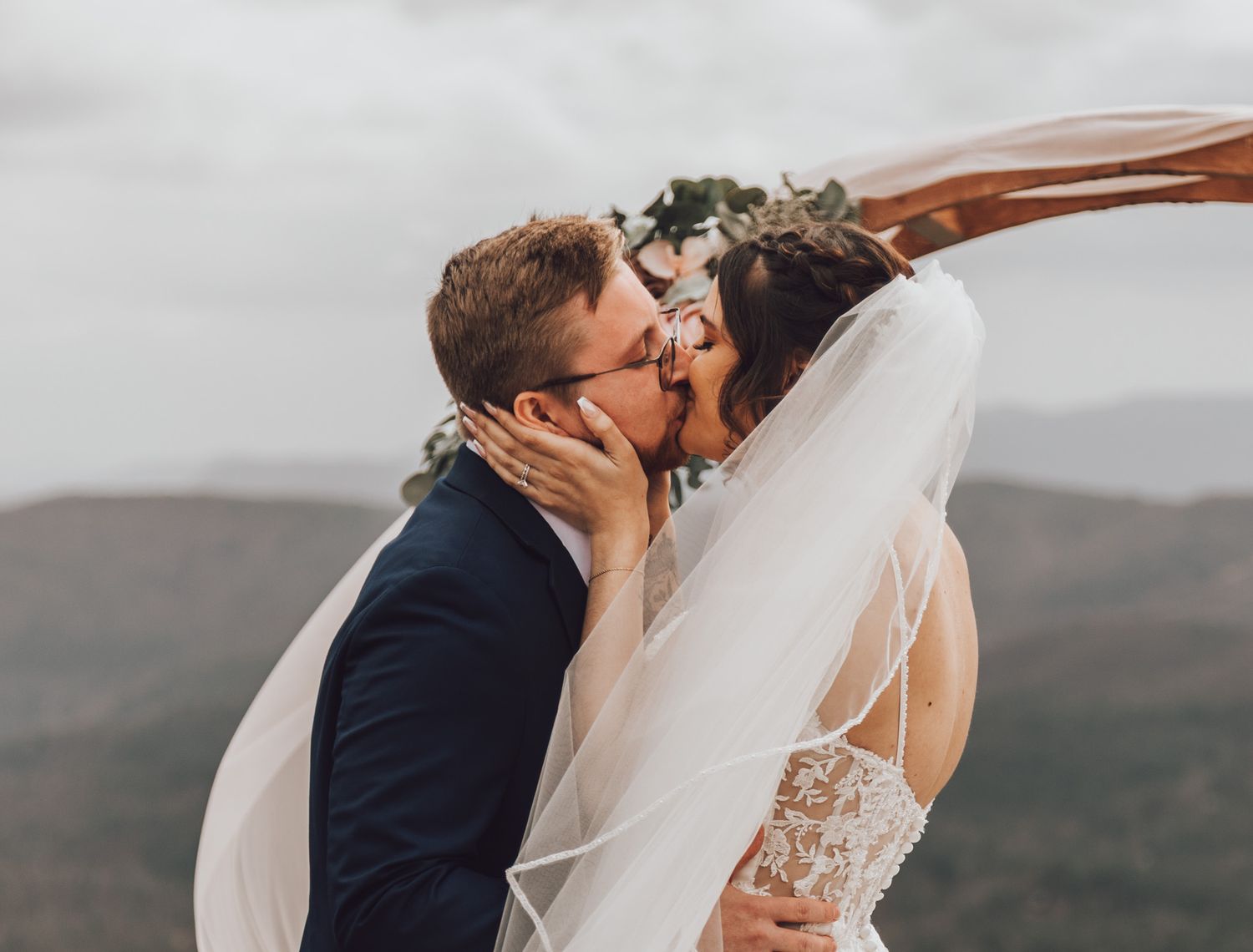 Romantic mountain wedding portraits showing couple embracing in scenic outdoor setting.