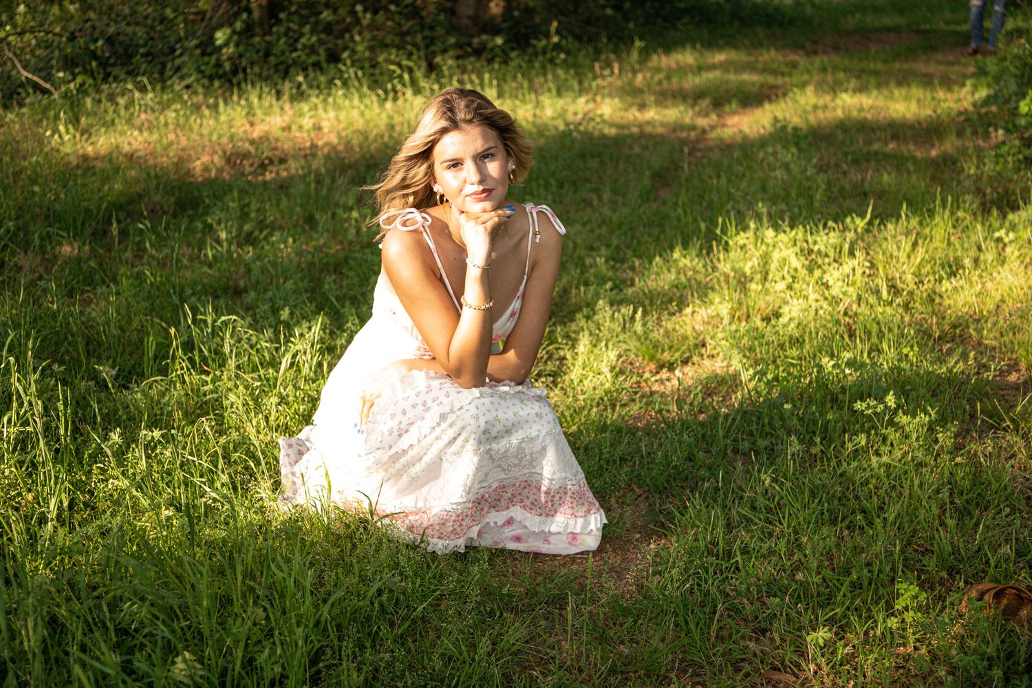 Summer portrait session in grassy field with white sundress and natural lighting.