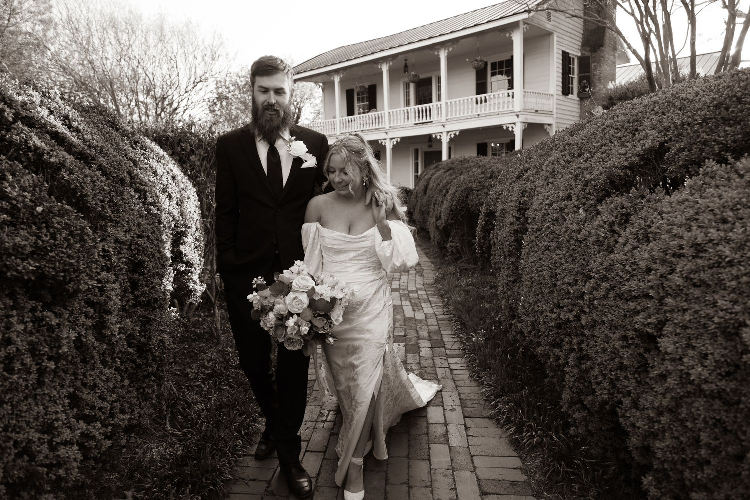 Traditional southern mansion with white columns and wrap-around porch sets the scene for a wedding.