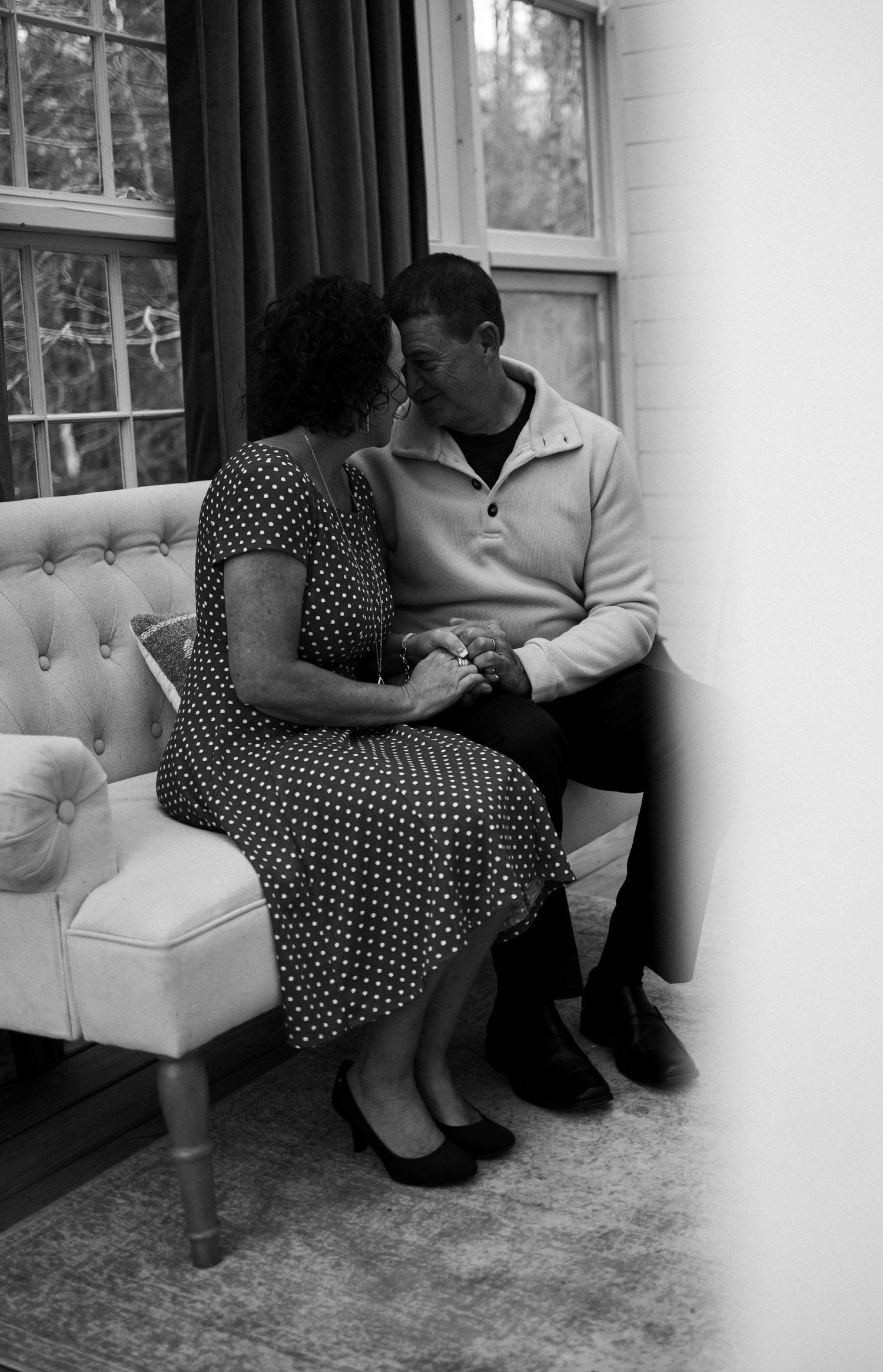 A series of black and white photos showing two people sitting close together on a couch in different poses.