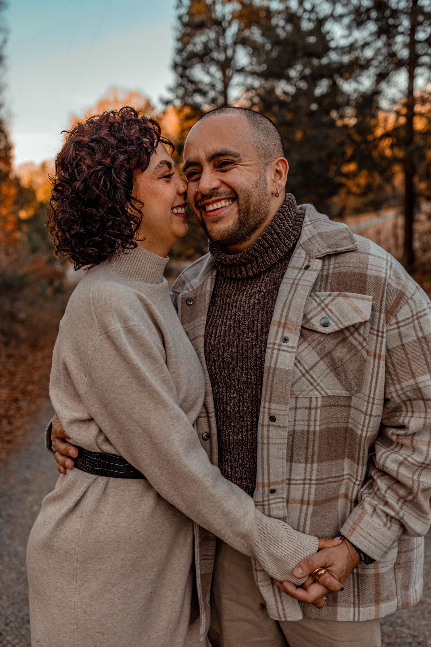 A couple shares intimate moments at sunset while wearing cozy fall outfits in a series of romantic outdoor photos.