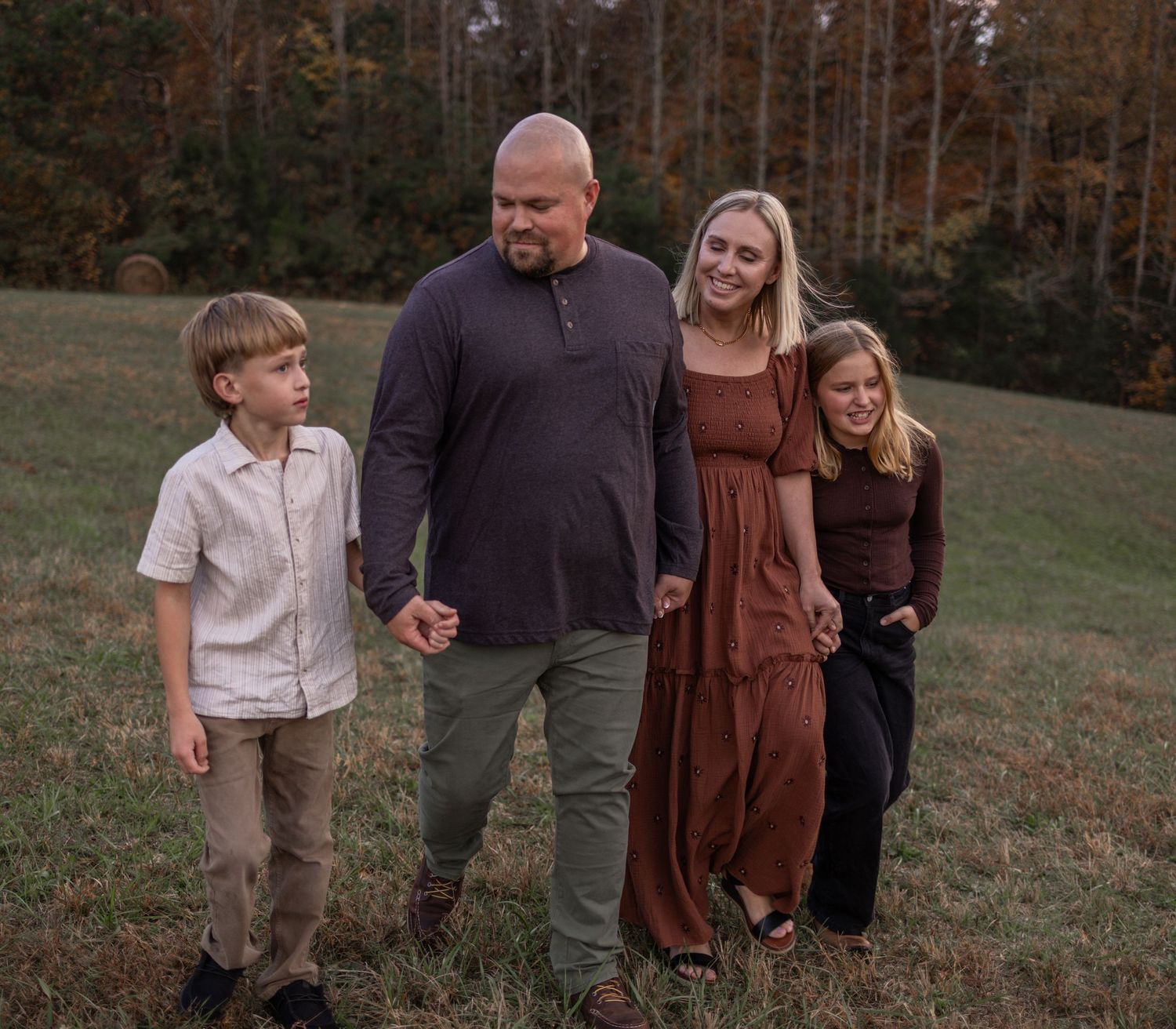 Family spending time together outdoors in a rustic field setting during autumn evening.