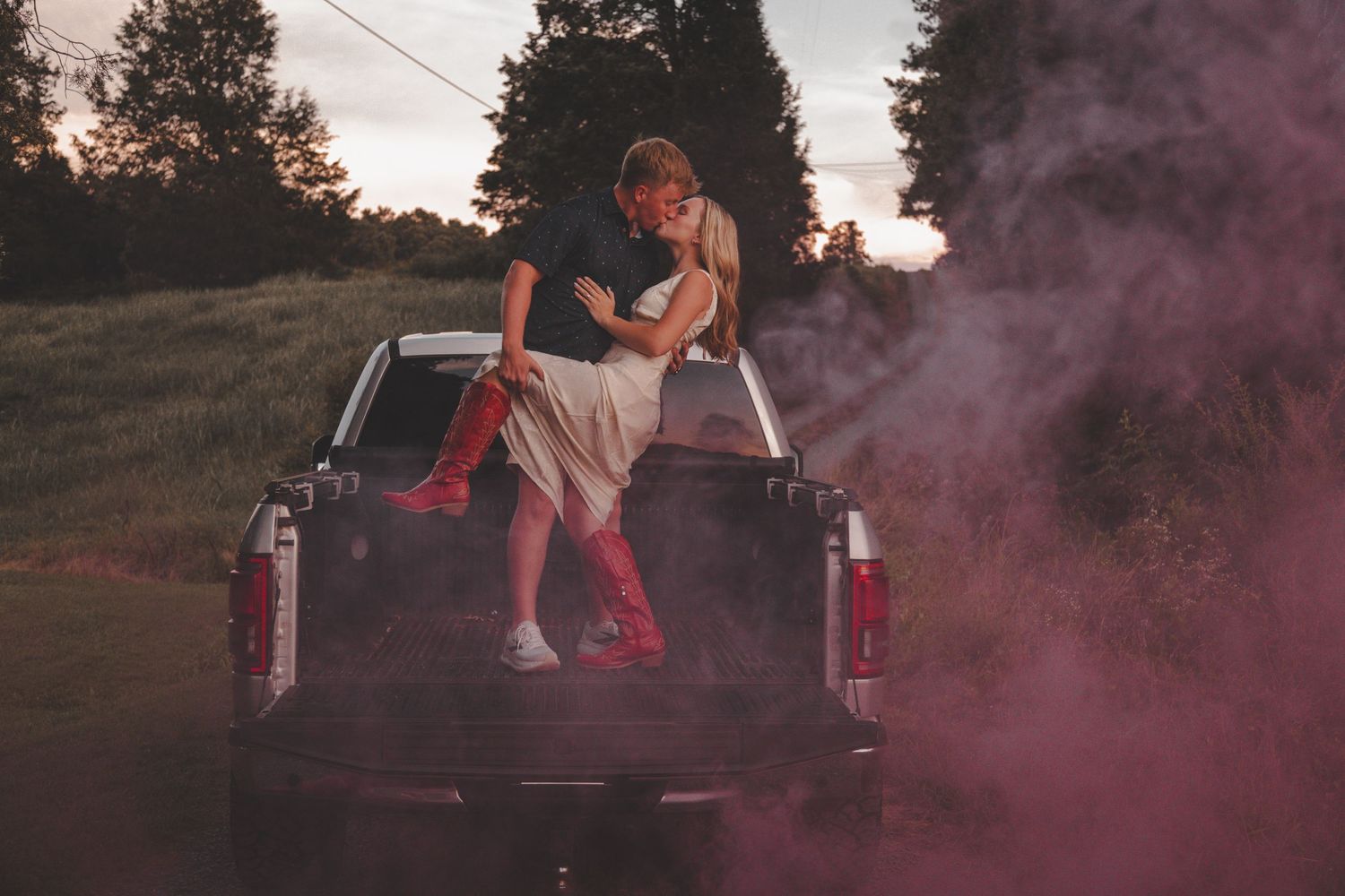 A romantic scene with pink smoke and a pickup truck at sunset.
