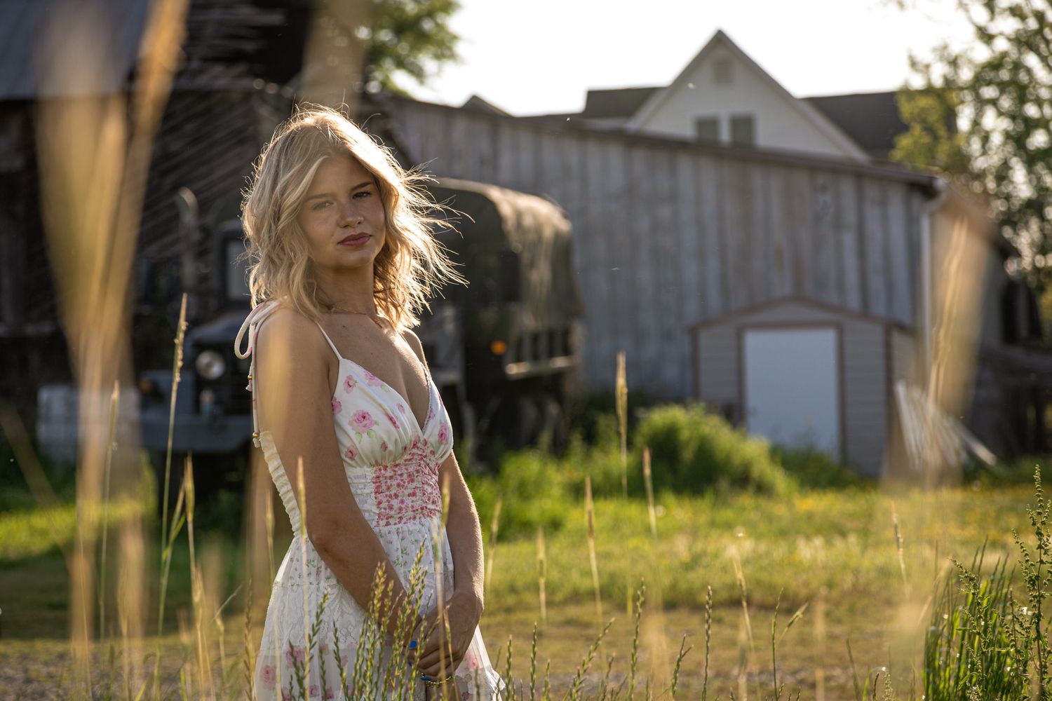 White sundress catching evening light with rustic barn in background.