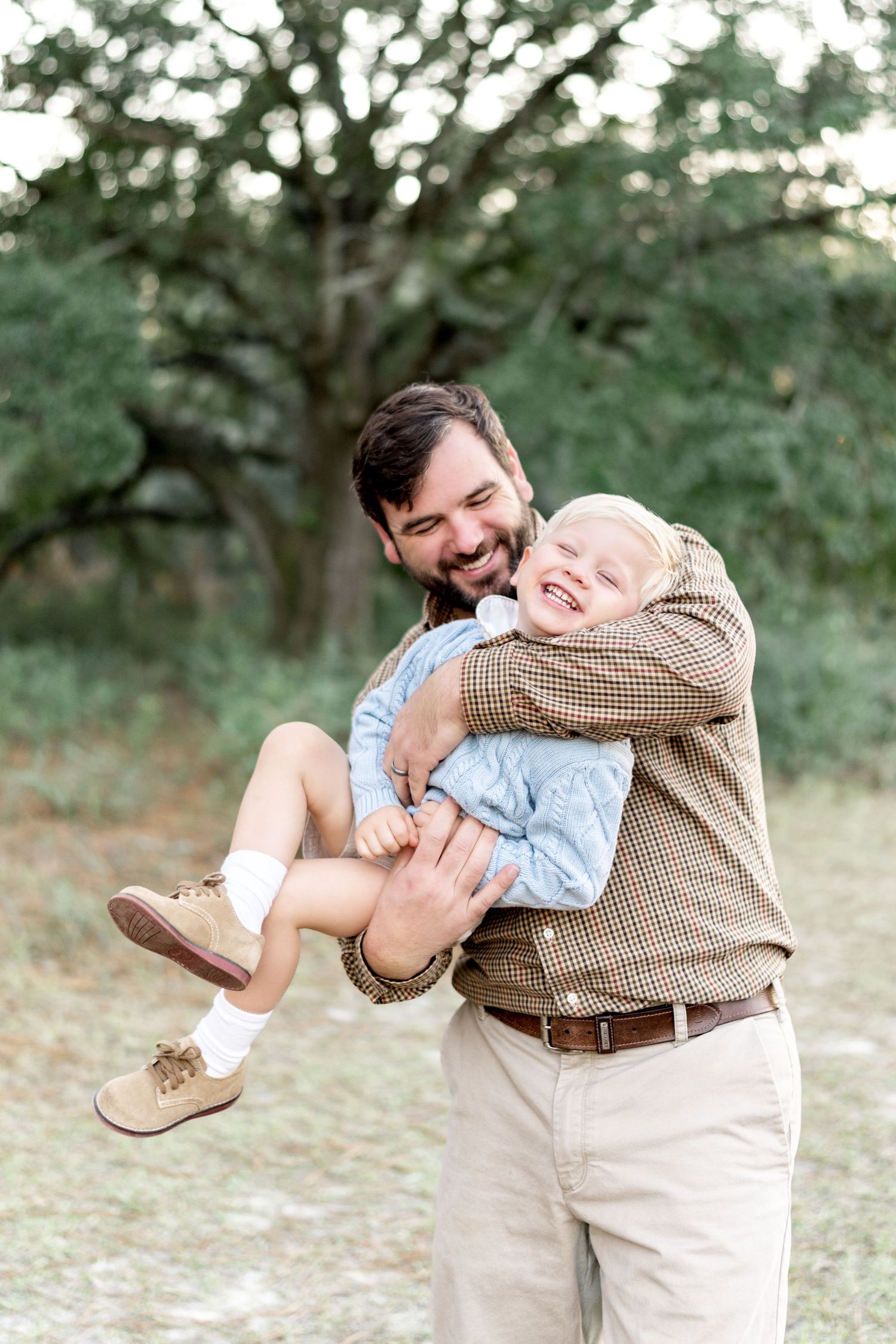A joyful outdoor portrait shows a tender moment of play and laughter between two people in a natural setting.