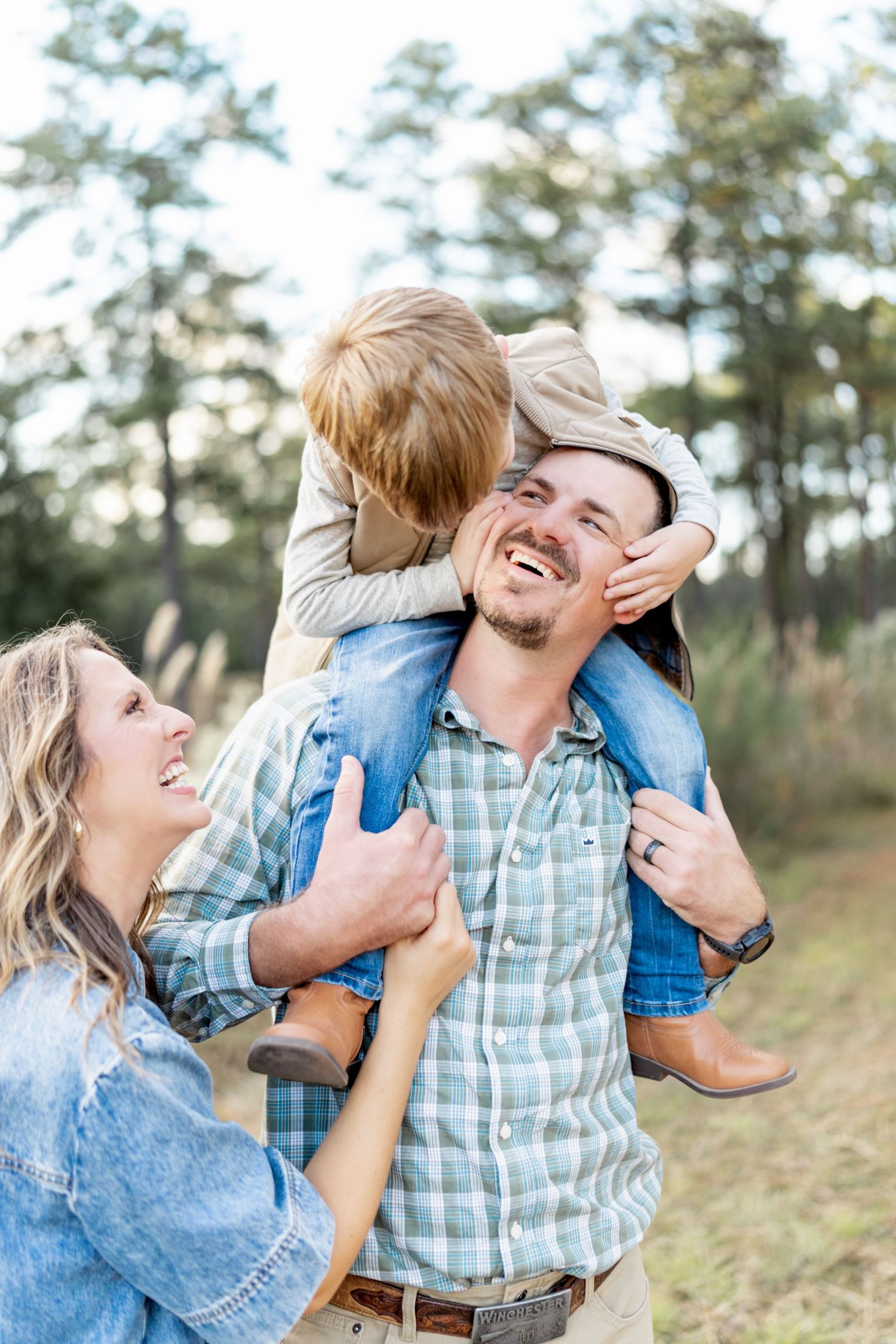 A family shares joyful moments together in a natural outdoor setting with pine trees in the background.