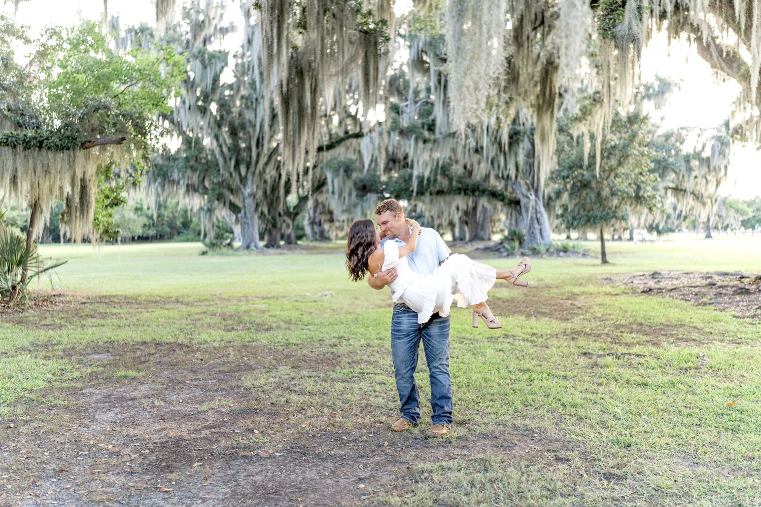 A couple photo session under Spanish moss-draped trees in a park setting located in Mandeville Louisiana