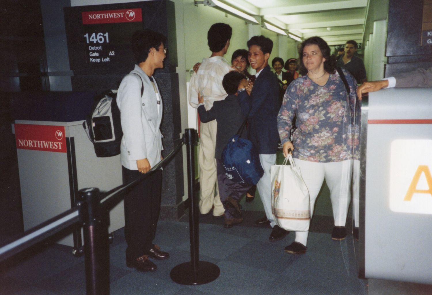 Passengers boarding Northwest Airlines flight 1461 at an airport gate, waiting in line with carry-on luggage.