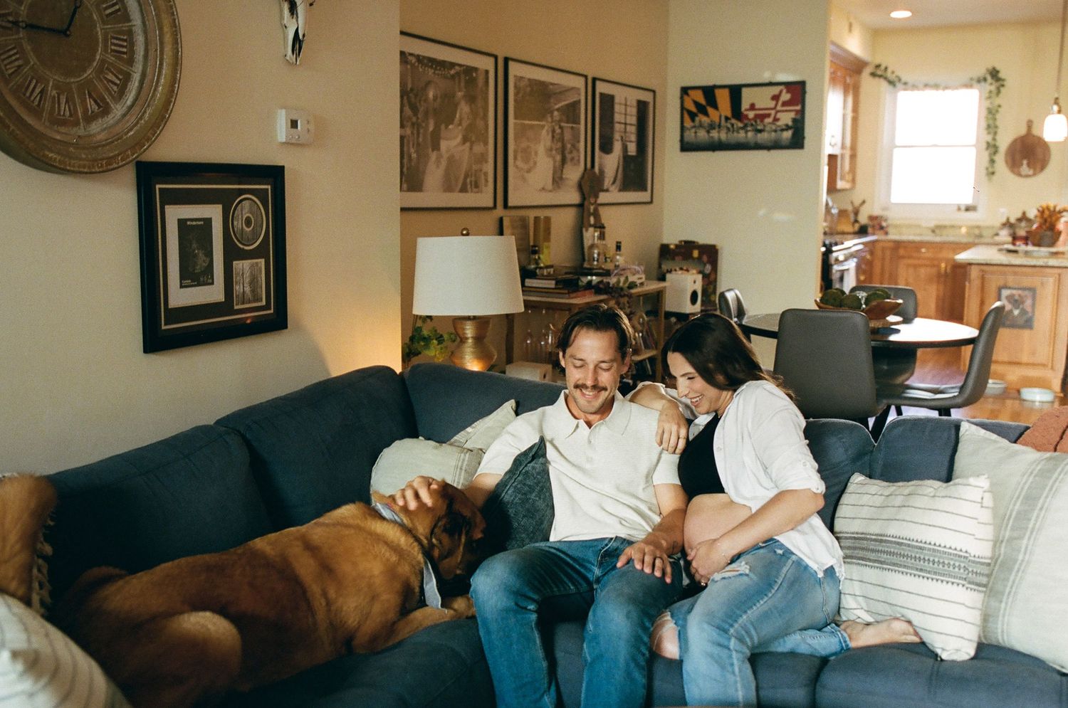Couple sitting together on a blue sofa with their dog in a cozy living room.