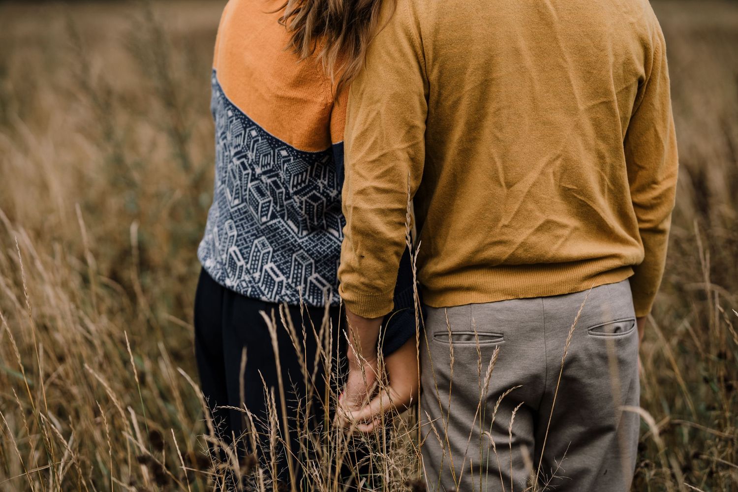 A couple holding hands on a field, romantic photoshoot with autumny vibes