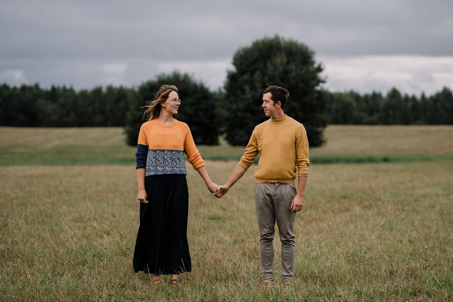A couple holding hands in a field, romantic photoshoot with autumny vibes