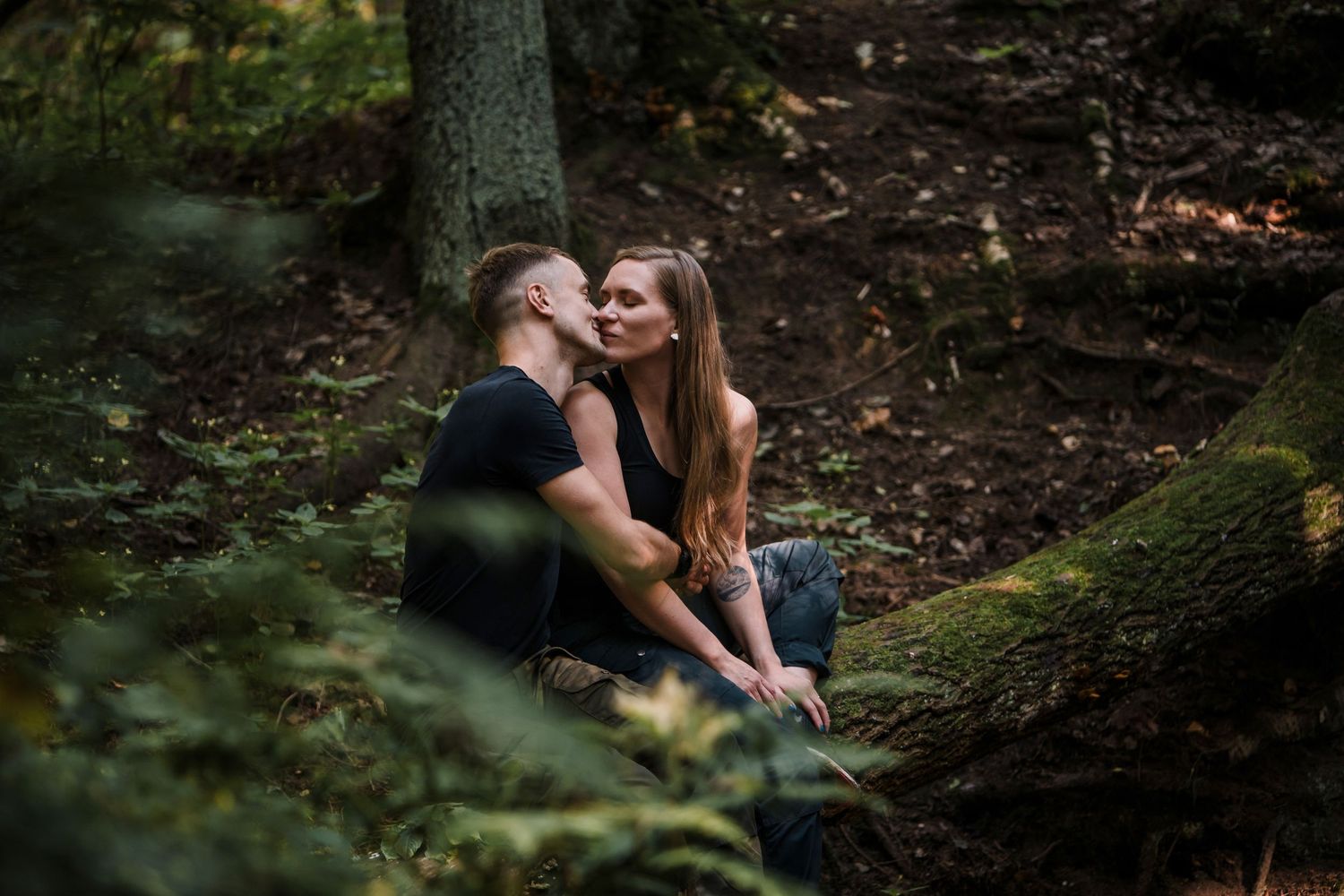 Couple in a forest kissing each other captured from between the tree leaves