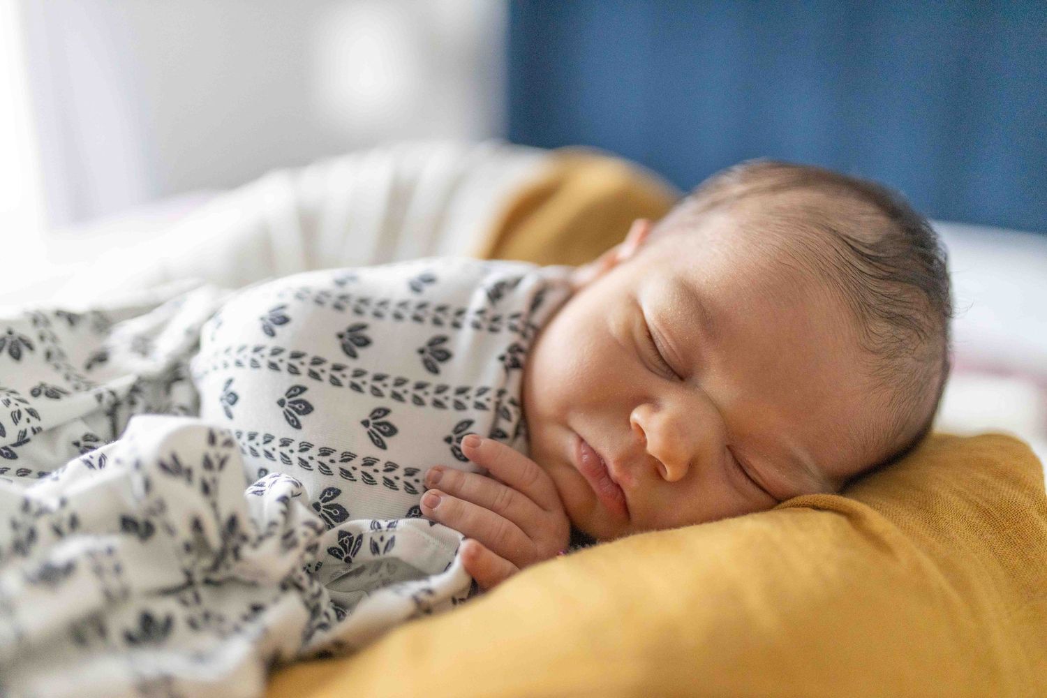 Newborn baby boy lying on the bed with soft blankets sleeping chubby cheeks at home newborn session  Sunshine North Melb Victoria