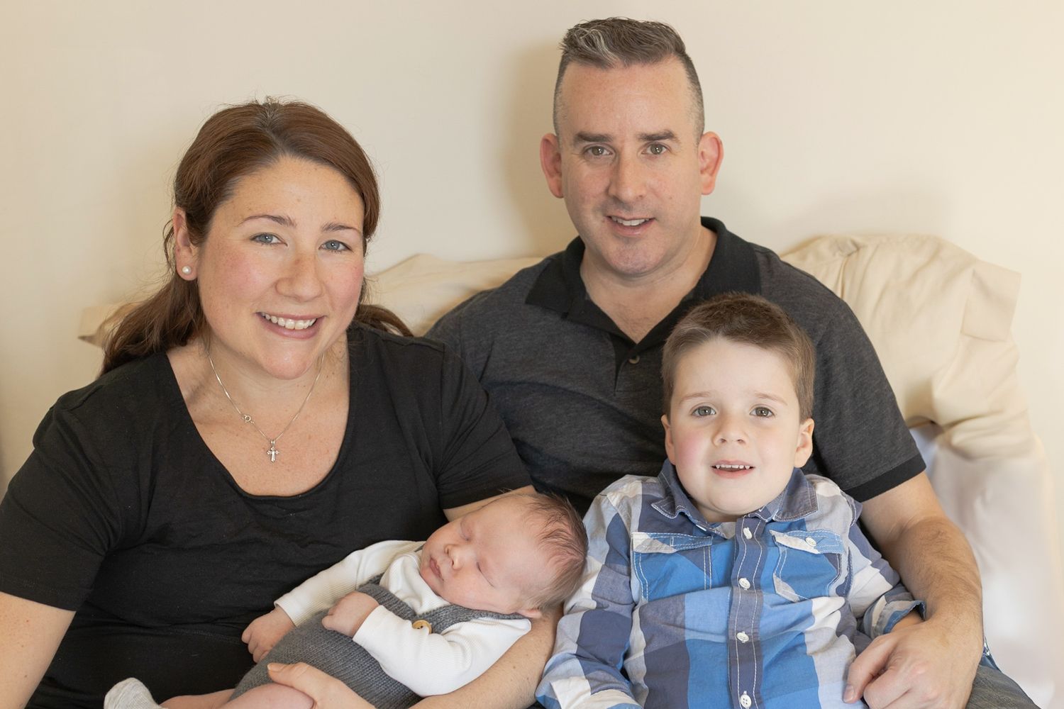 Family sitting on the bed cuddling and smiling together at home newborn session  Moonee Ponds Melb