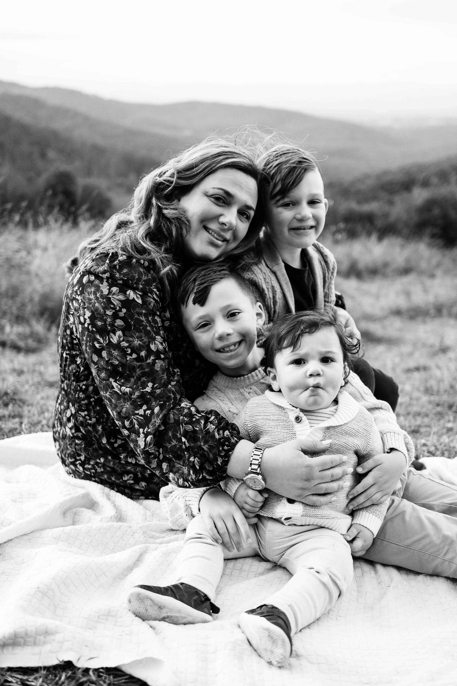 mother and sons 3 sons cuddling and smiling, baby boy squishing his cheeks