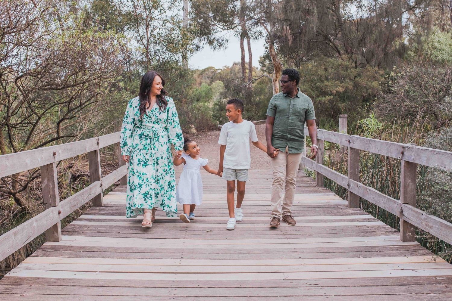 Family walking across a bridge happy all holding onto each other. Family of four parents and brother and sister Newport ,Melbourne, Victoria