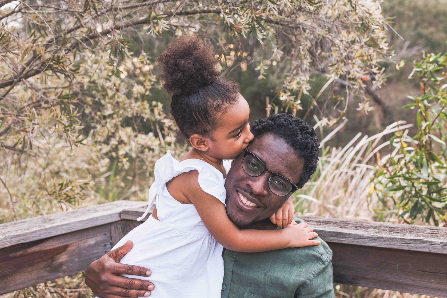 Daughter kissing dad on the head and giving a big hug. Newport Lakes, Melbourne Victoria