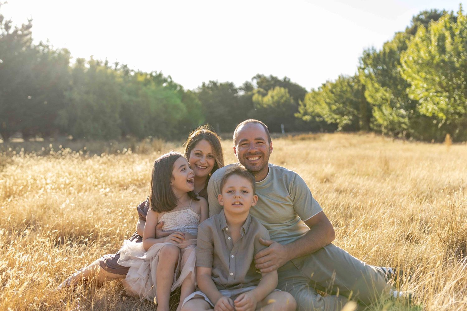 Family sitting together in a field smiling comfortably Outdoor at home family session Gisborne Melb Vic