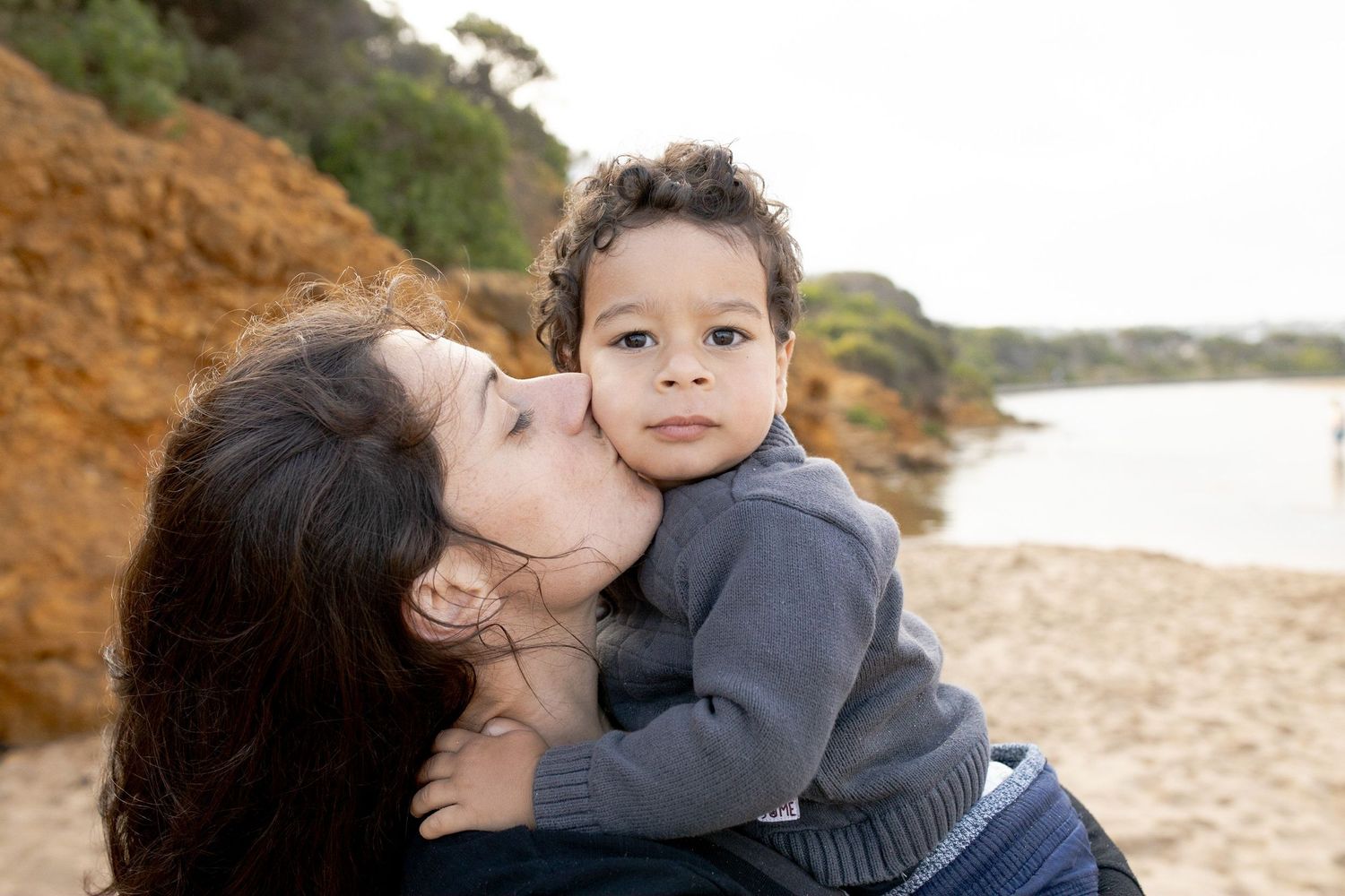 Mum kissing her toddlers cheek at the beach Outdoor family session Torquay