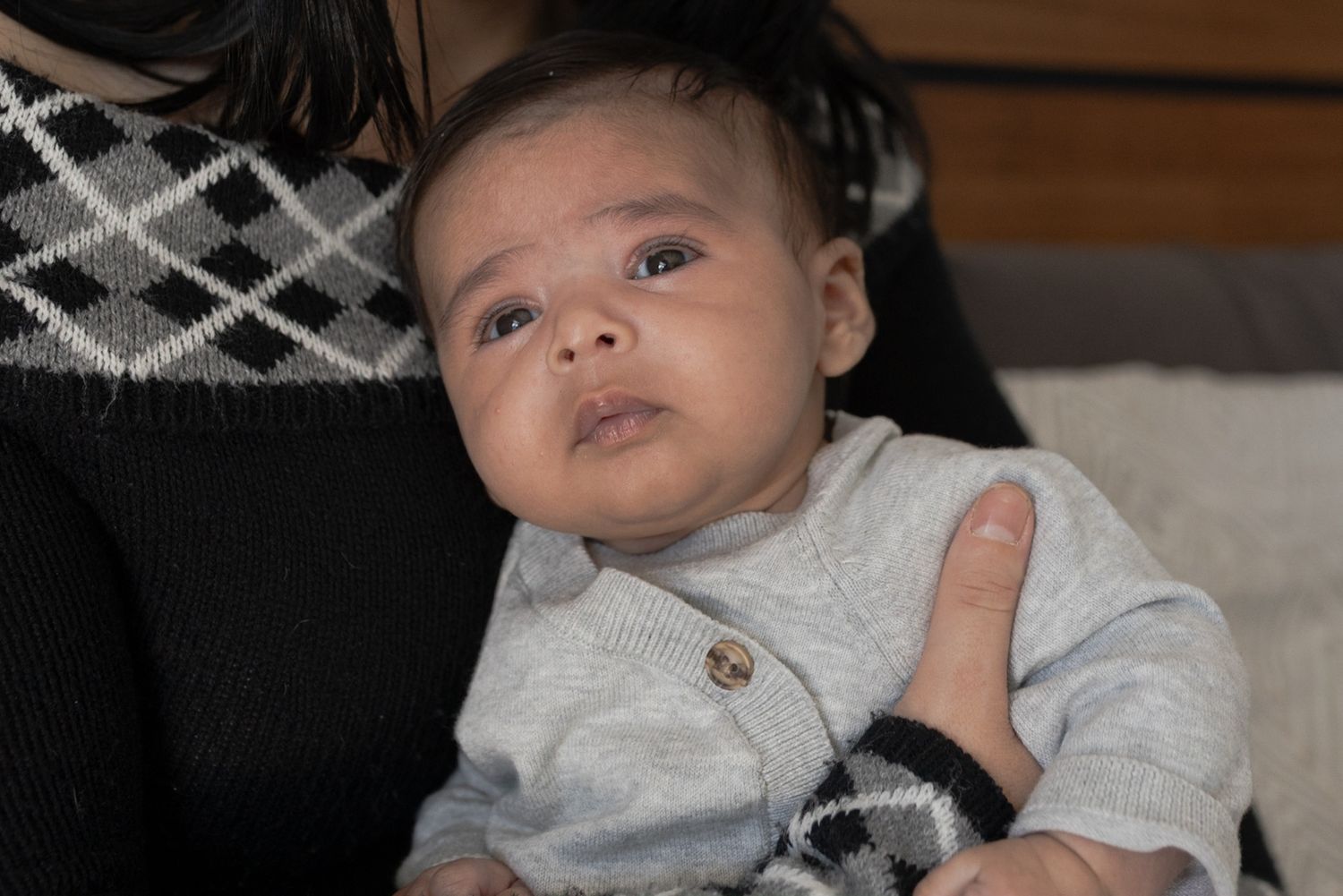 Baby boy sitting on mum looking out the window In home newborn session Sunshine North Melb Vic