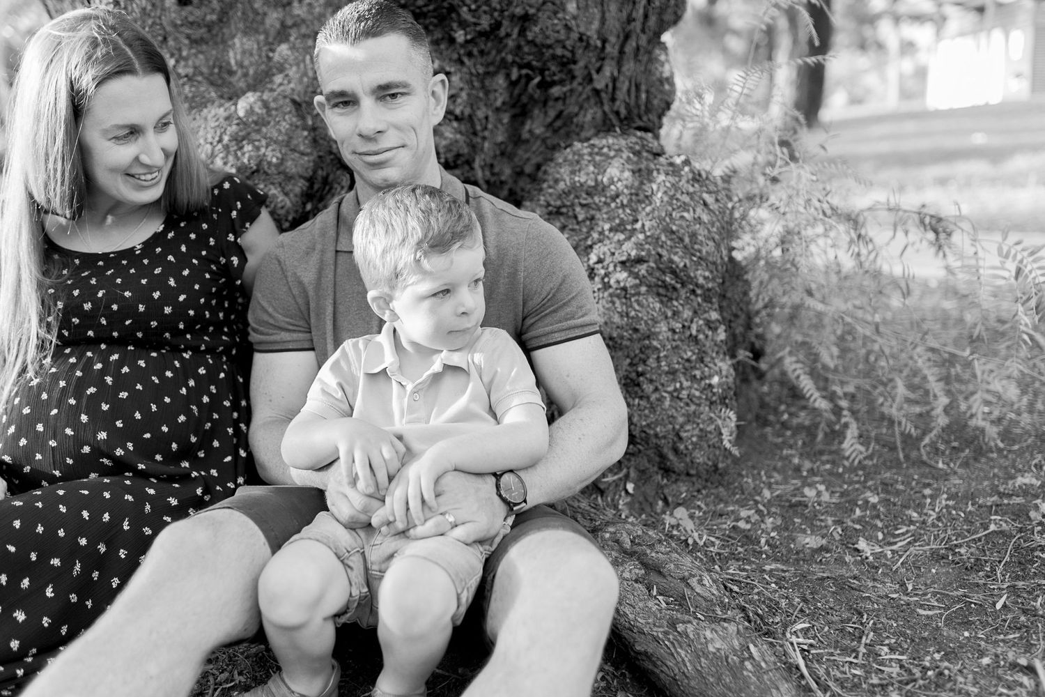 Family of three sitting together under a tree. Outdoor maternity session Coburg Melbourne Victoria