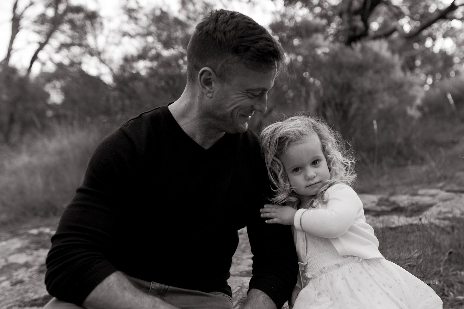 Little girl holding onto dads arm, dad smiling at little girl. Girl twirling in a field big smileOutdoor family session Macedon Ranges Melb