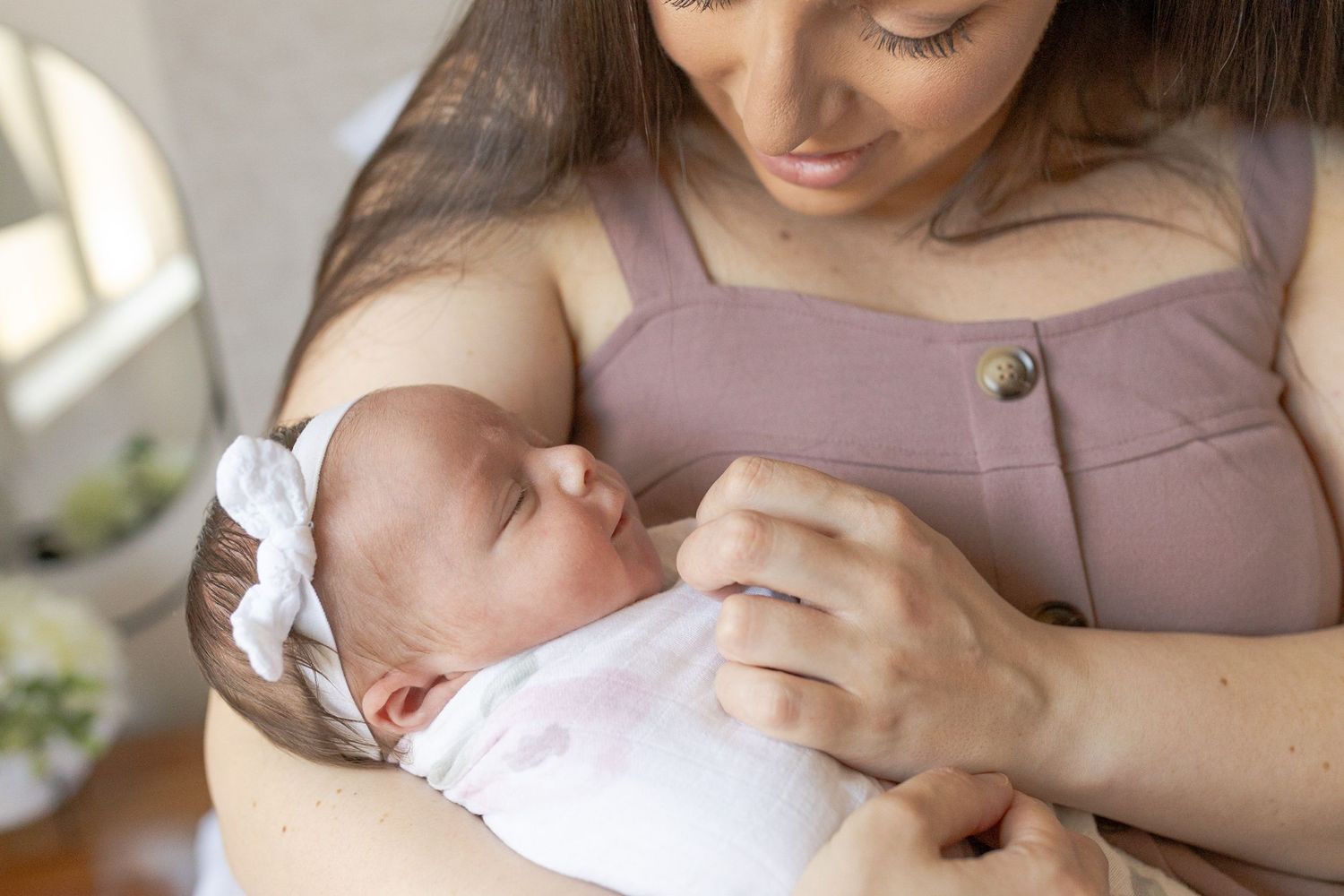 Mum holding her newborn baby girl in her arms looking at her sitting in a rocking chair at home newborn session Caroline Springs Melb Vic