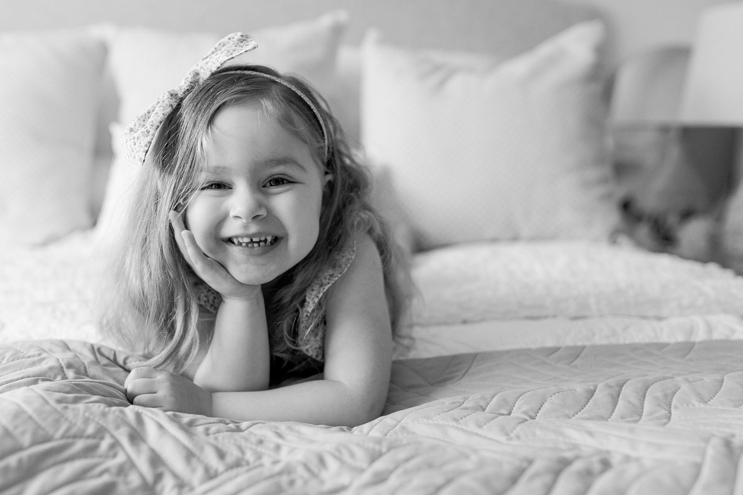 Big sister lying on the bed smiling happily at home newborn session Caroline Springs, Melbourne, Victoria