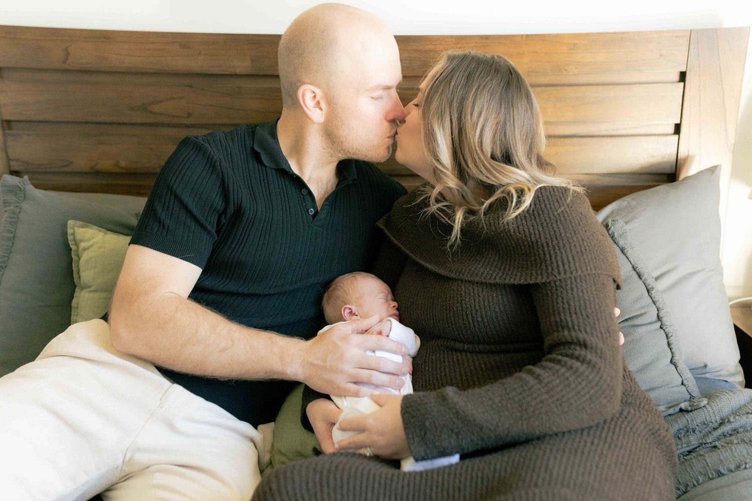 Parents kissing while holding newborn between them