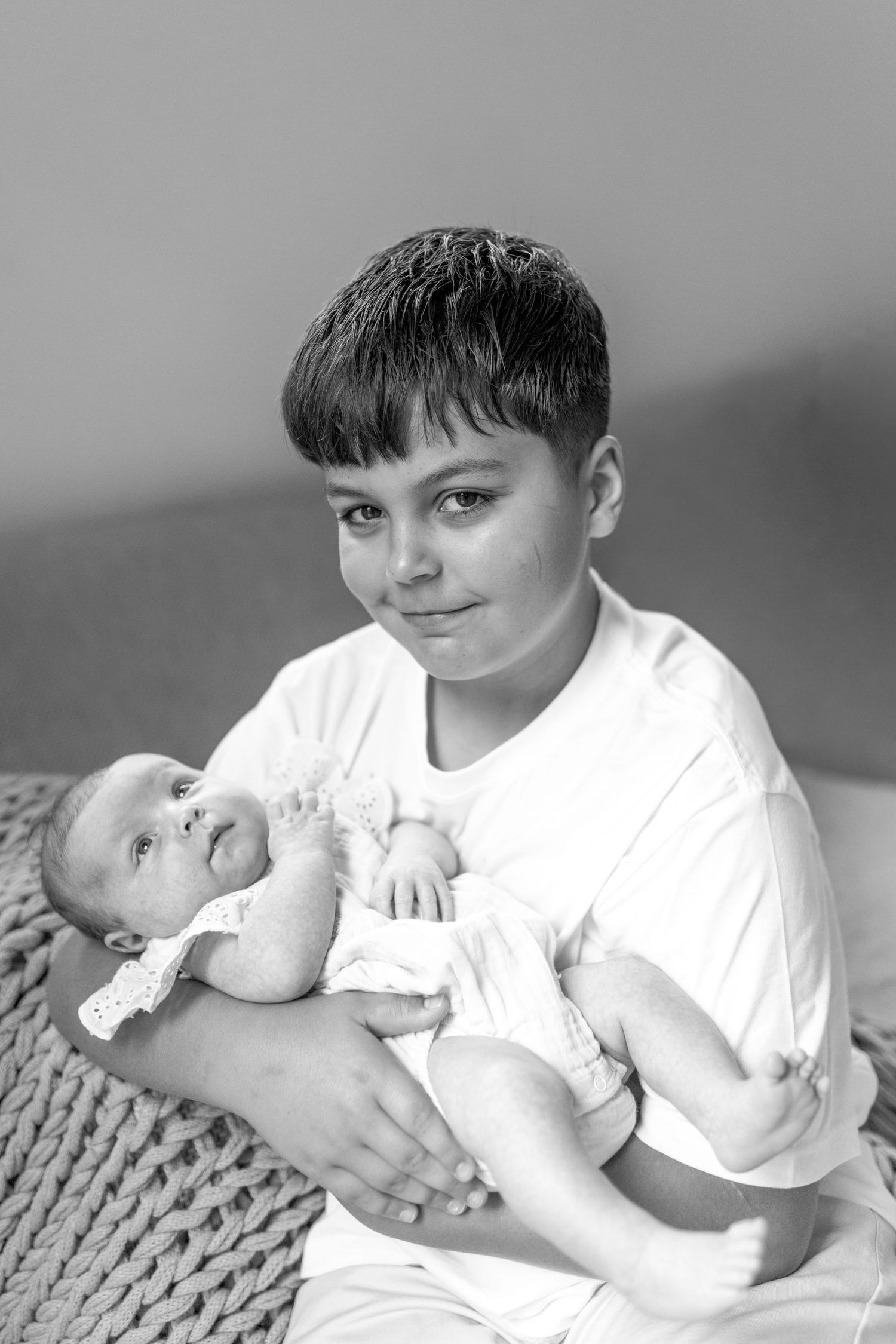 Big brother holding his baby sister and looking at the camera