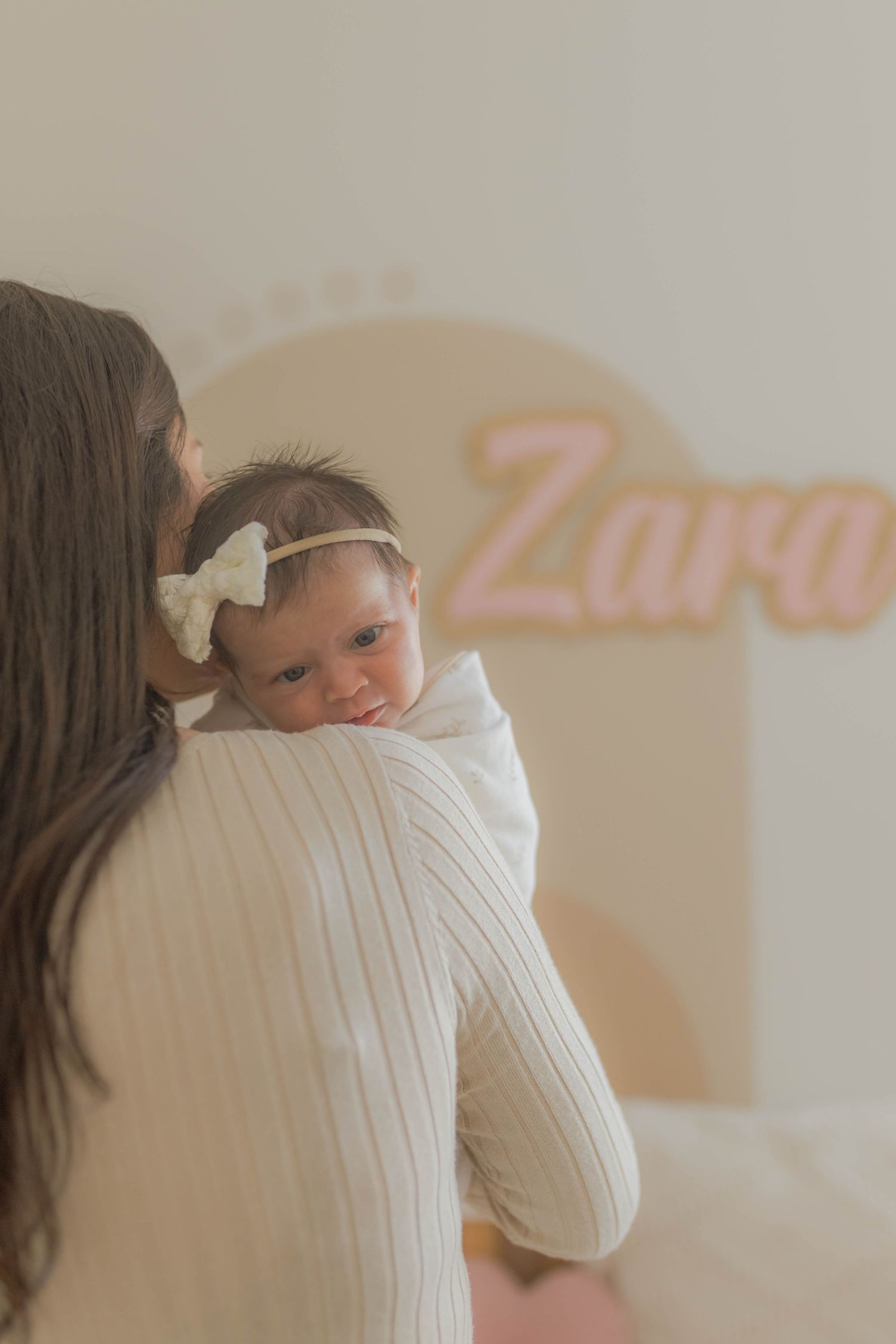 Newborn baby girl peeking over her mothers shoulder in her nursery with her name on the wall Point Cook Melb Vic