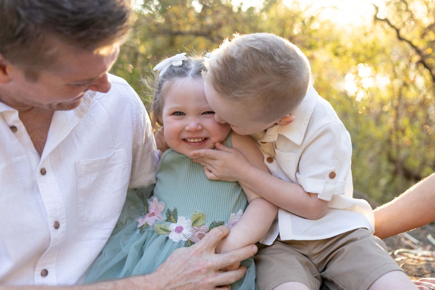 Siblings cuddling brother kissing his sister parents looking on, Outdoor family session  Newport Lakes, Melb, Vic