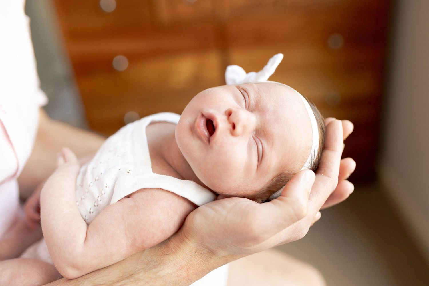 Dad holding newborn baby girl in his hands while dad is looking down at home newborn session Caroline Springs Melb Victoria