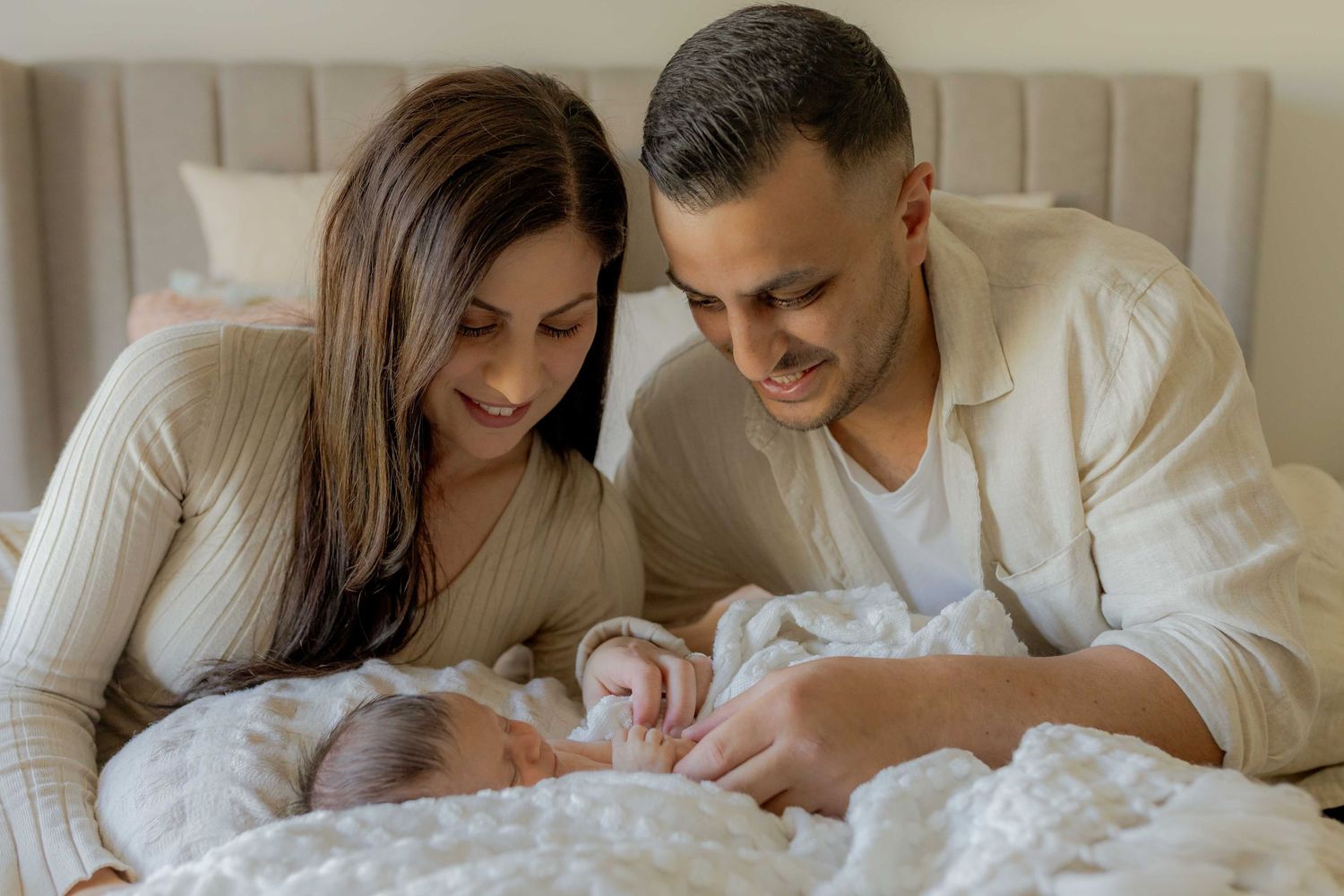 At home newborn session, parents looking down on their baby girl lying on their bed. Point Cook, Melb, Vic
