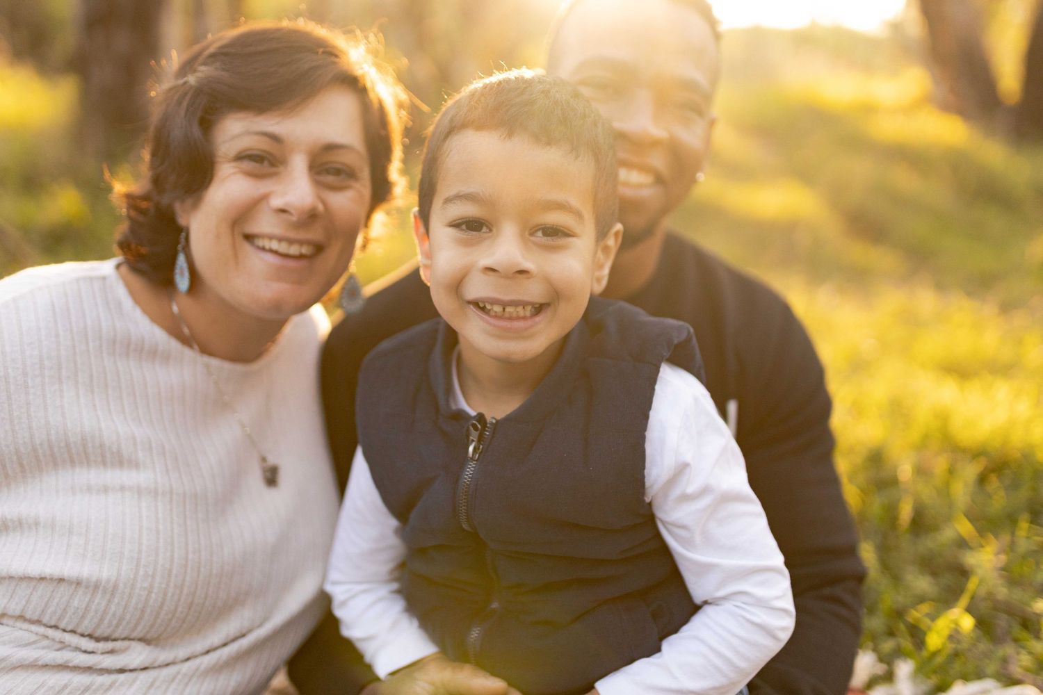 Family of three on a white blanket smiling Outdoor maternity session Sunshine Melb Victoria
