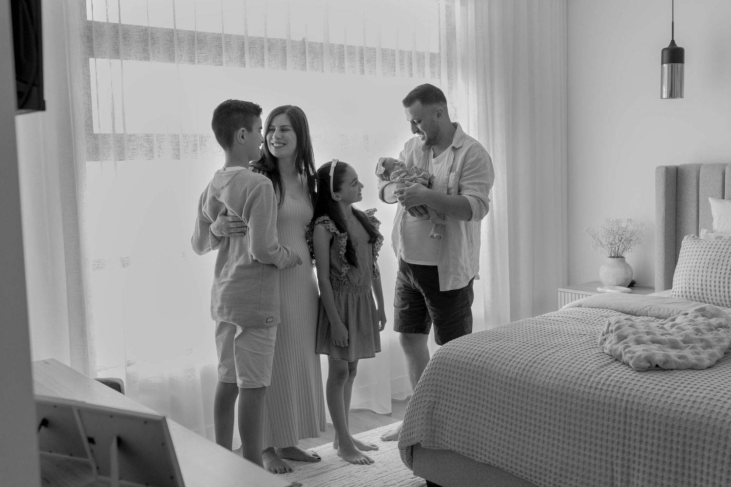 Family of five looking at each other in the master bedroom, father holding the newborn baby girl. Point Cook, Melbourne, Victoria