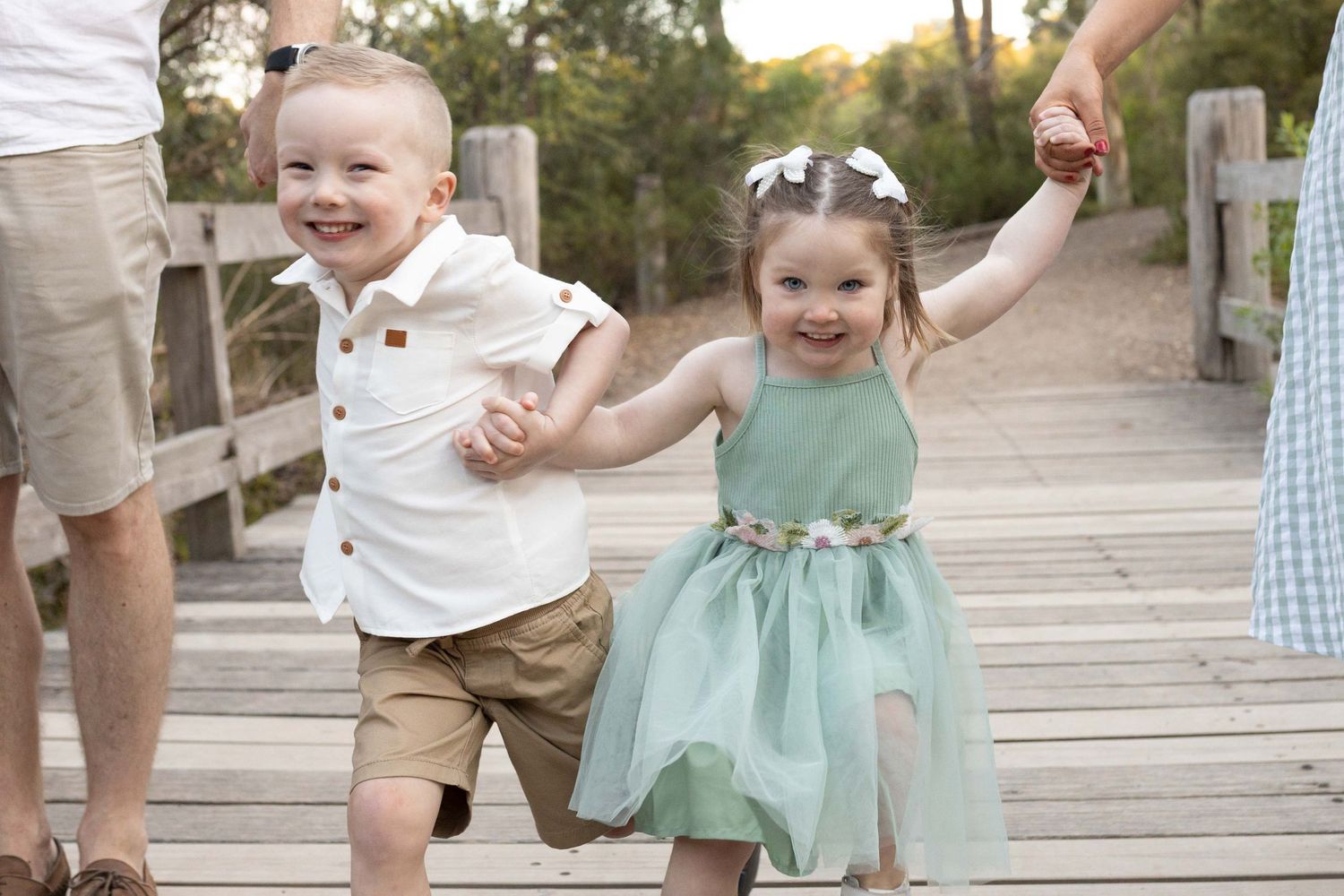 Excited young brother and sister holding hands running across the bridge Outdoor family session Newport Lakes, Melbourne, Victoria
