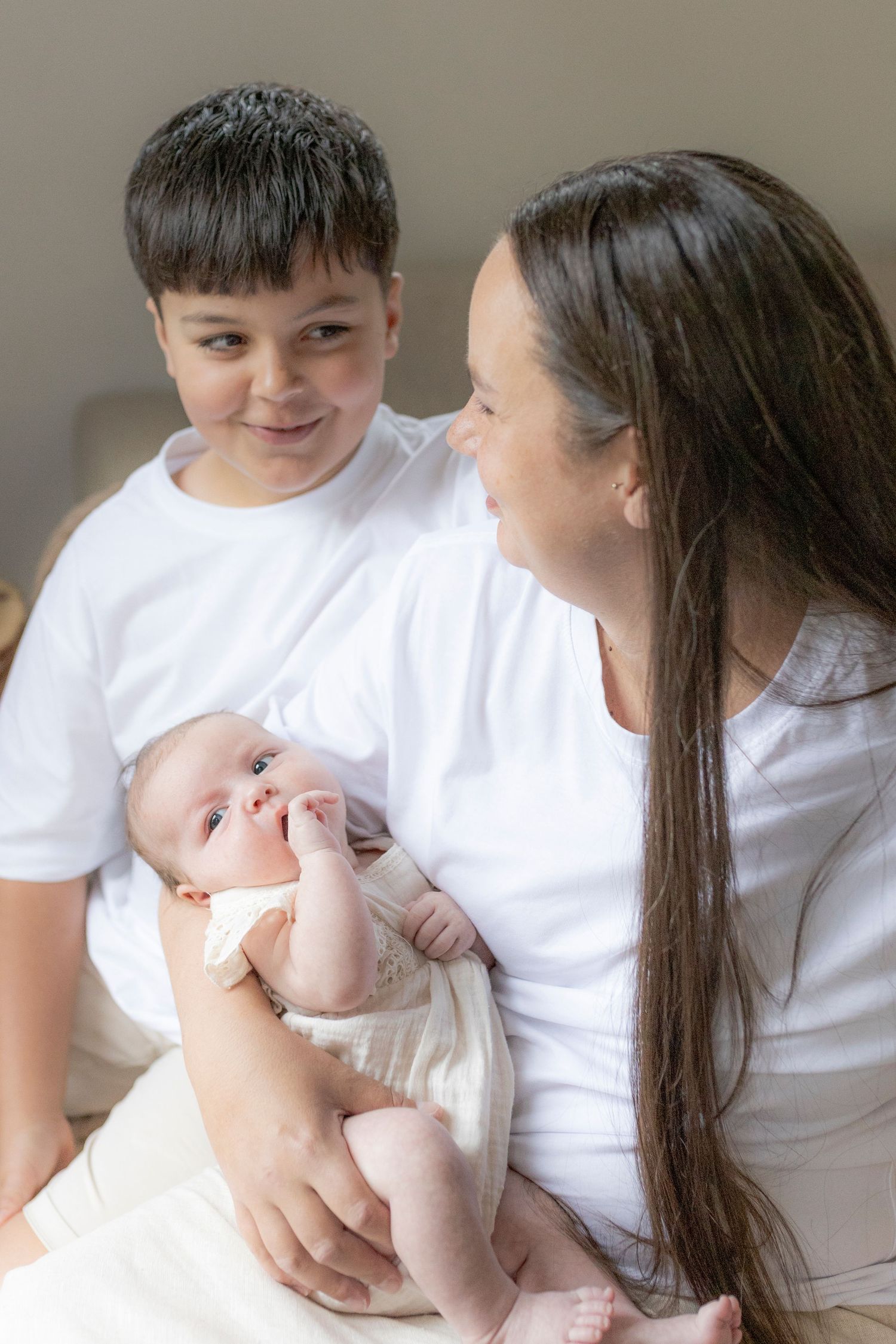 Mum and son smiling at each other with baby girl looking away