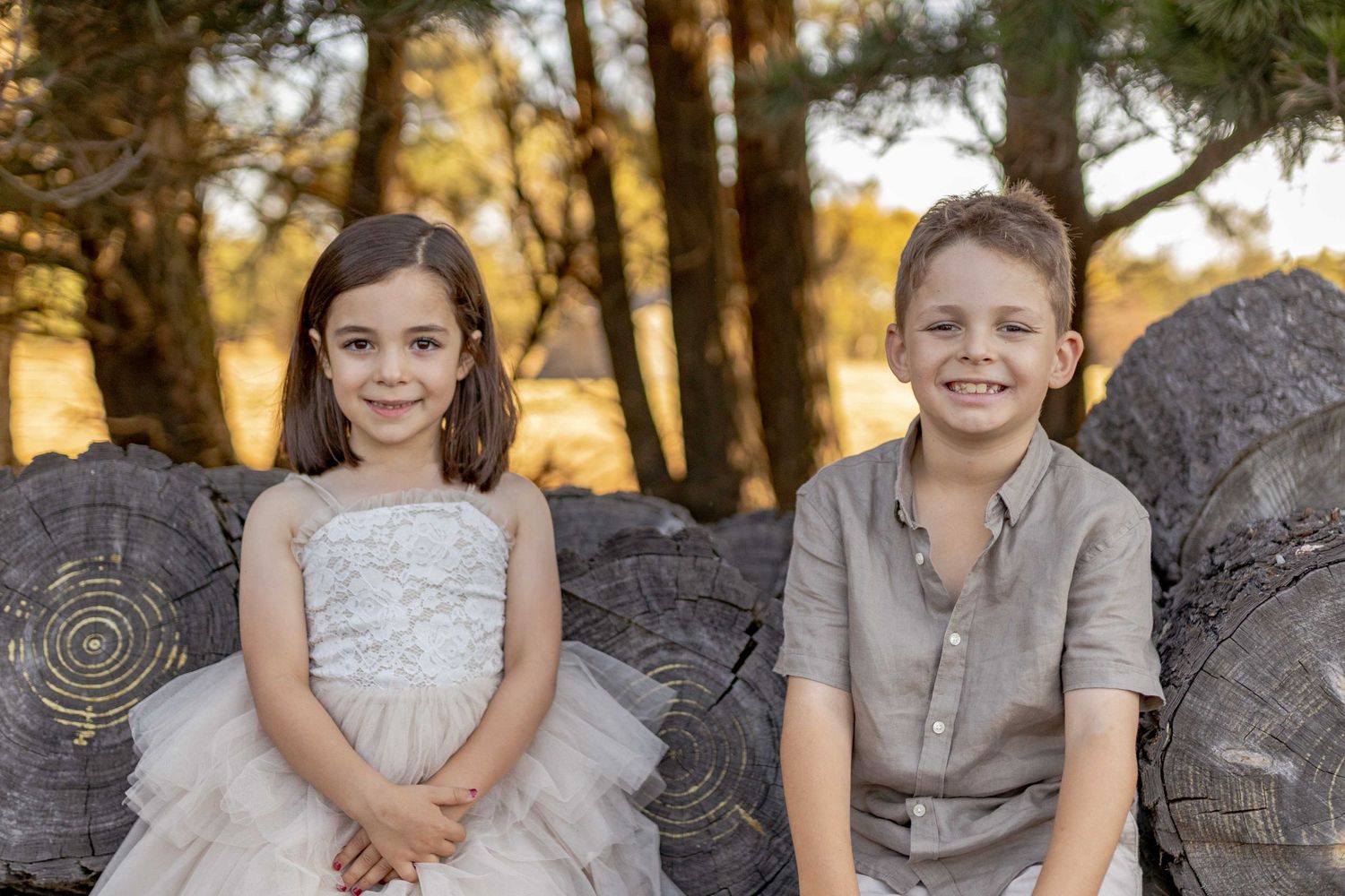 Brother and sister sitting on large logs of wood Outdoor at home family session Gisborne Melb Vic