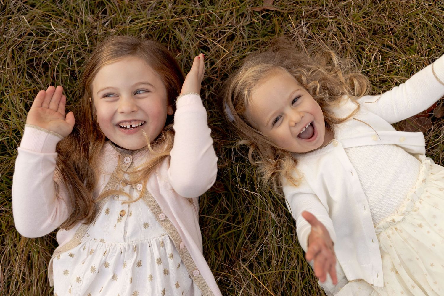 Sisters playing peek a boo will lying down in a field laughing and excited.  big smile Outdoor family session Macedon