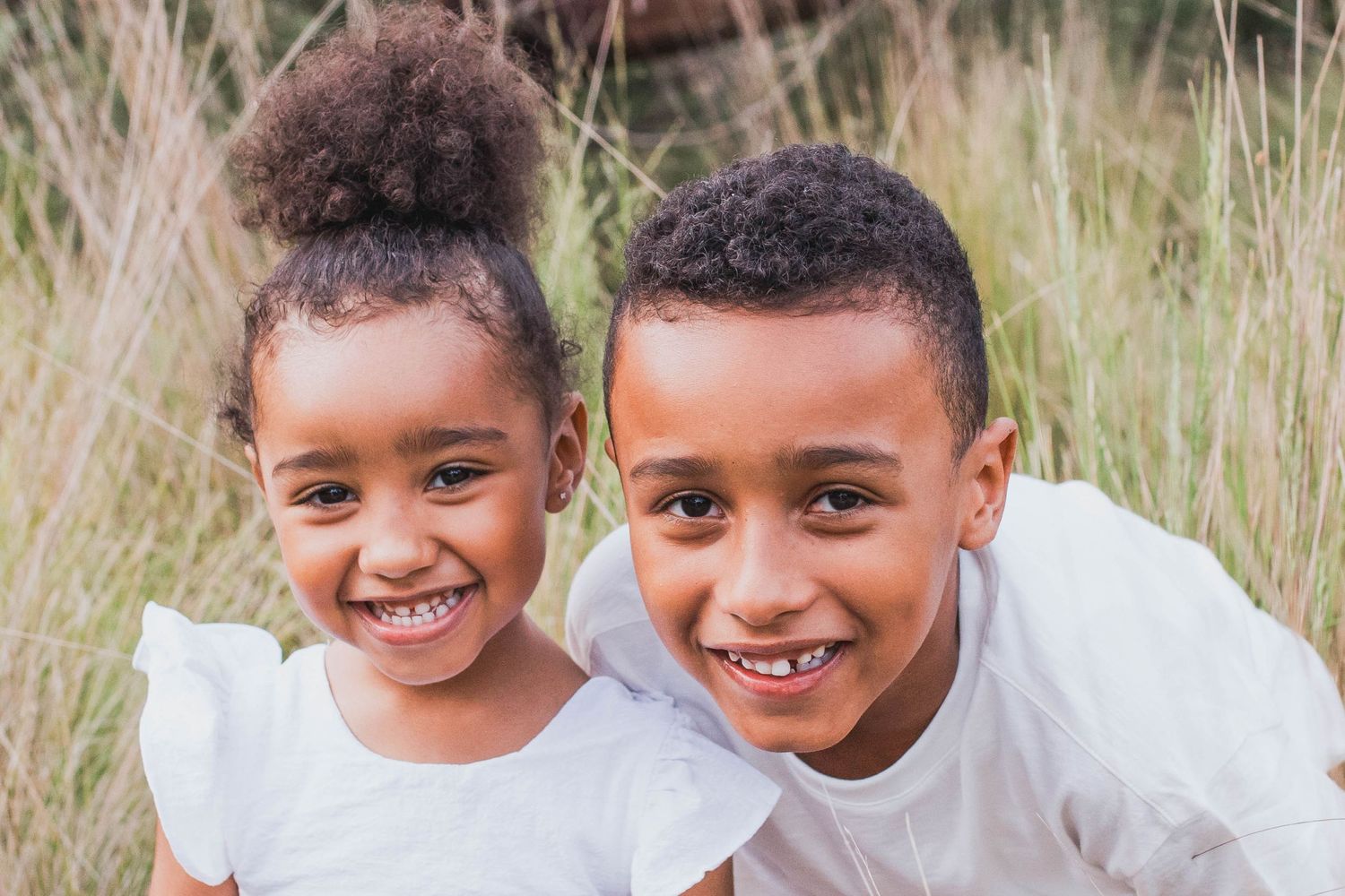 Siblings smiling close together family outdoor session in the tall grass, Newport Lakes Melb Vic