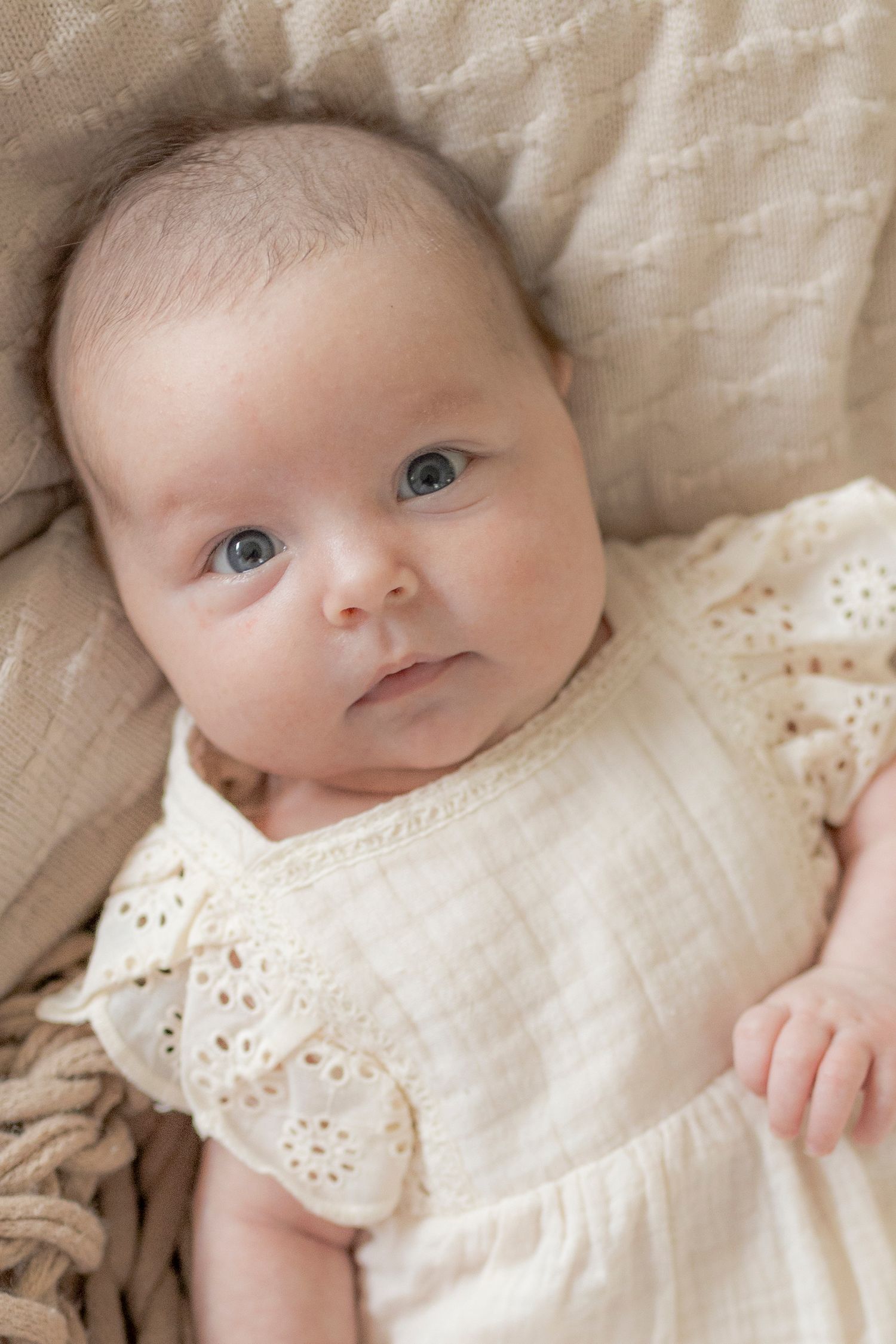 Newborn baby girl looking up at the camera surrounded by soft blankets Newborn photoshoot in Melbourne's West